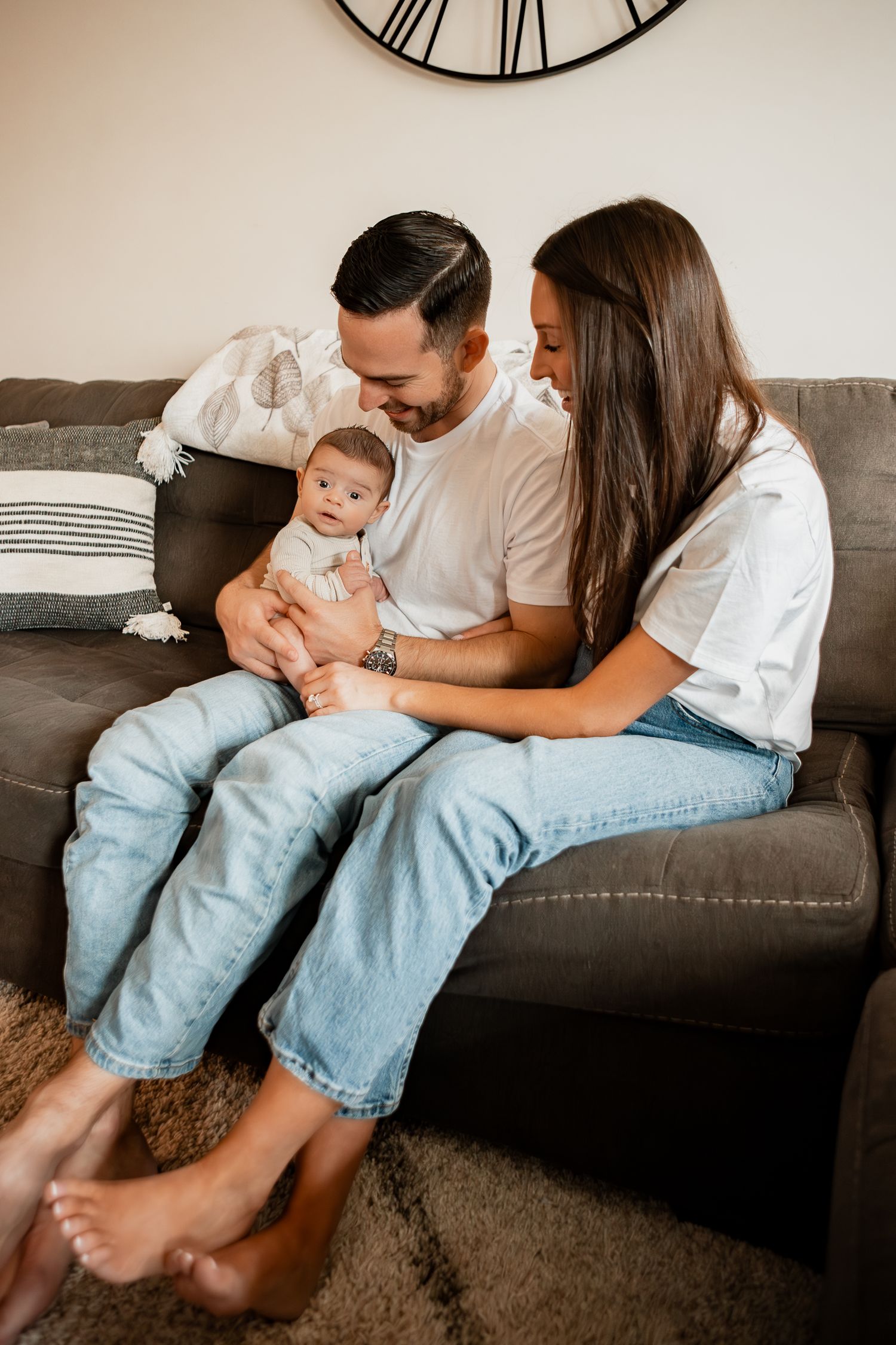 A cozy family moment relaxing together on a dark gray couch in a minimalist living room.