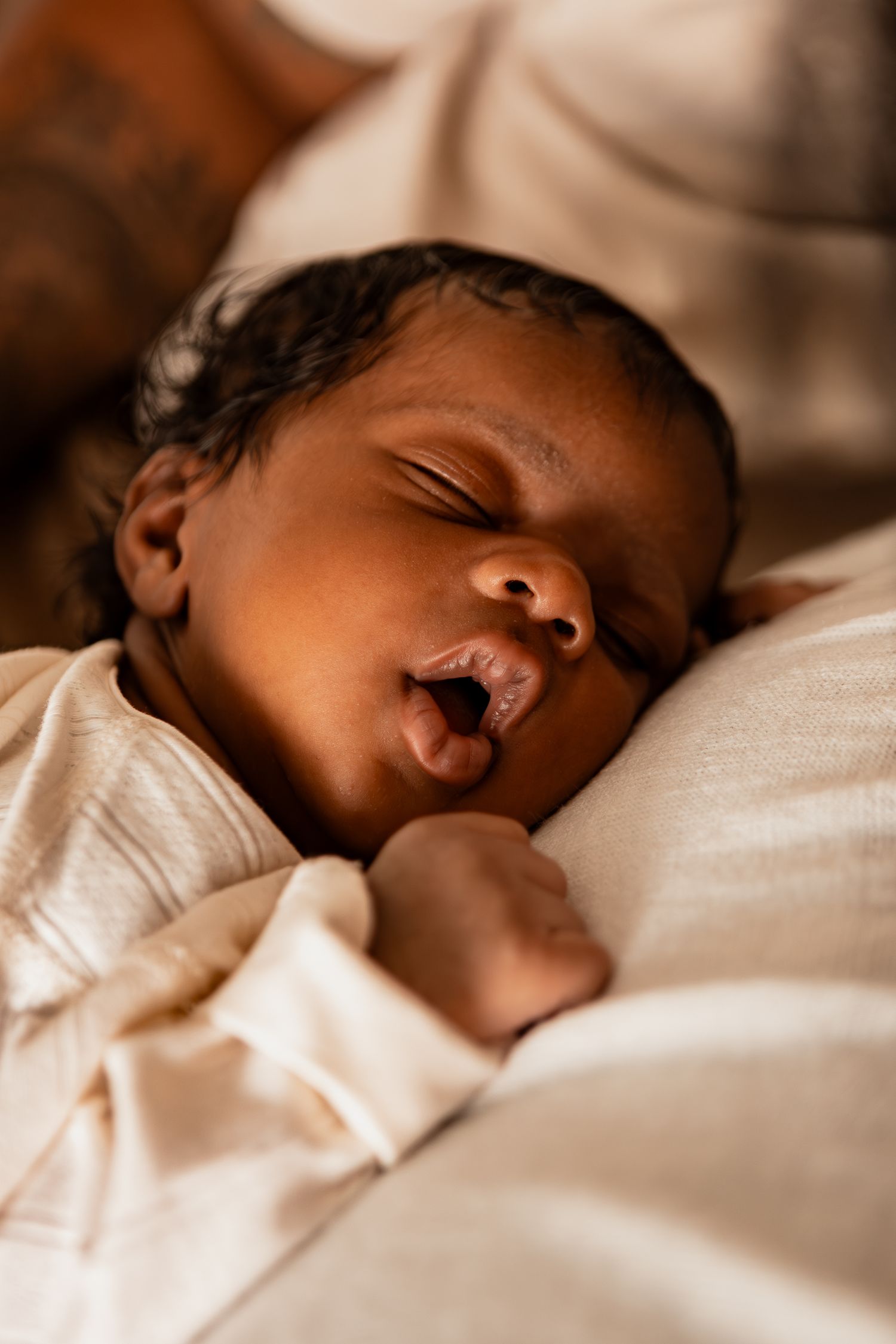 Close-up views of an infant sleeping soundly in white clothes against light colored bedding.