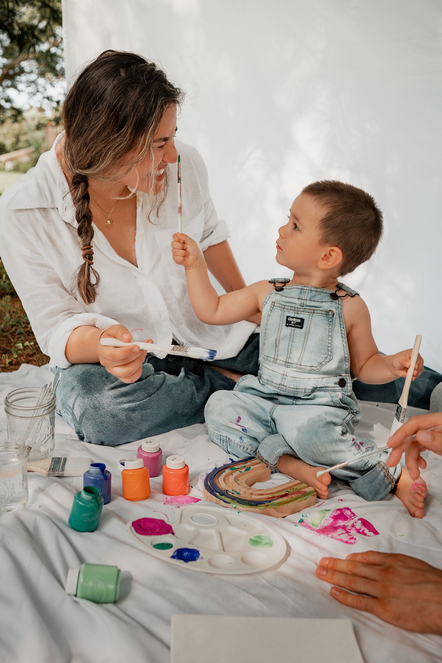 Creative painting session with colorful paints and brushes on a white surface.