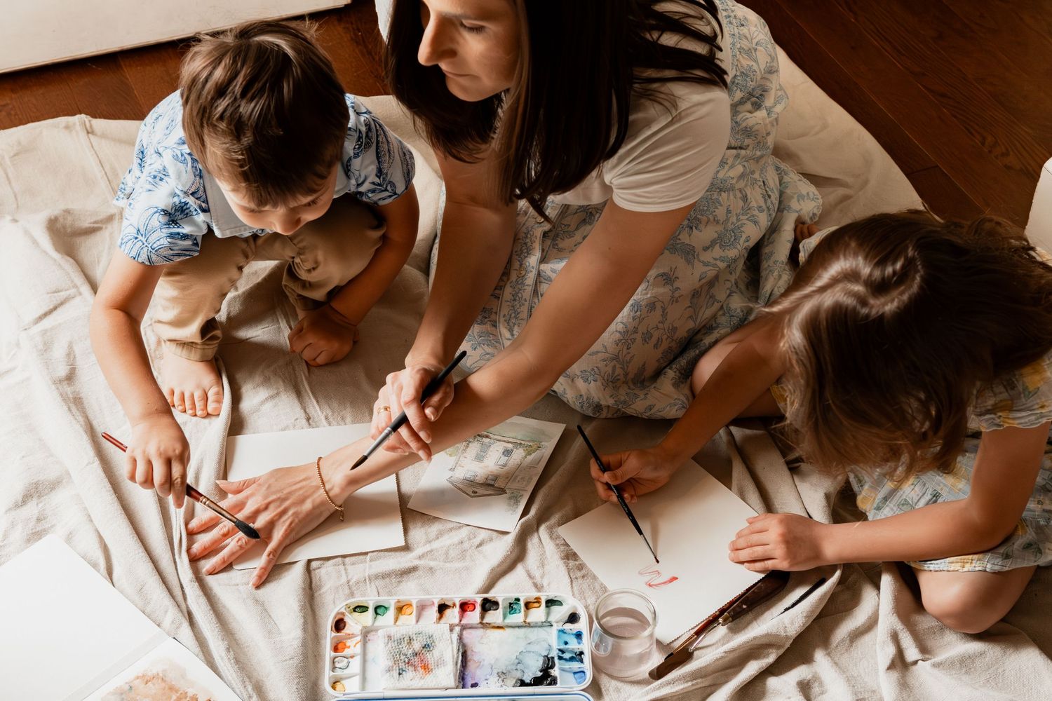 Multiple images showing children drawing with art supplies and crayons while seated at a table.