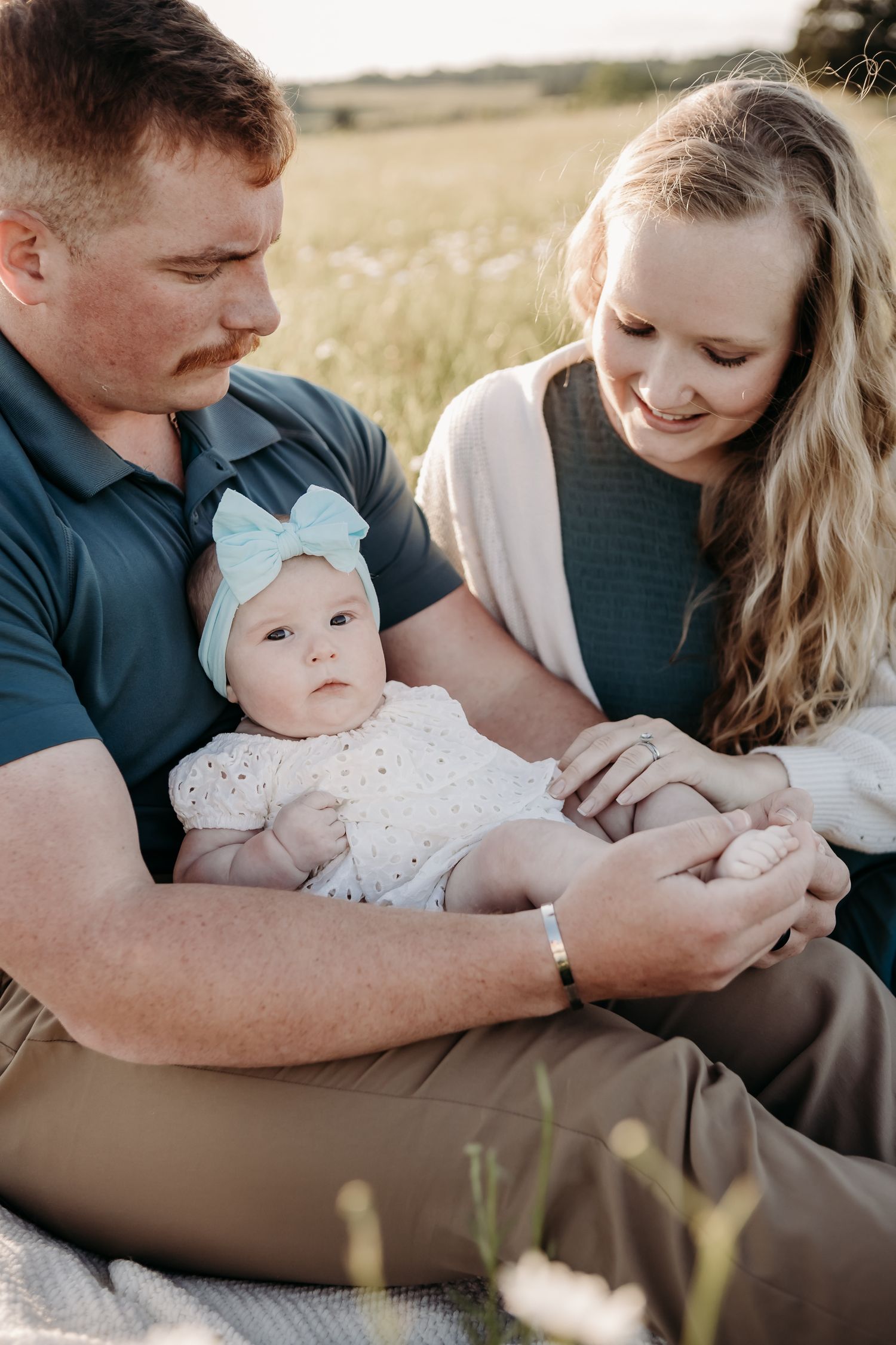 A family sits together in a sunlit field on a warm afternoon.