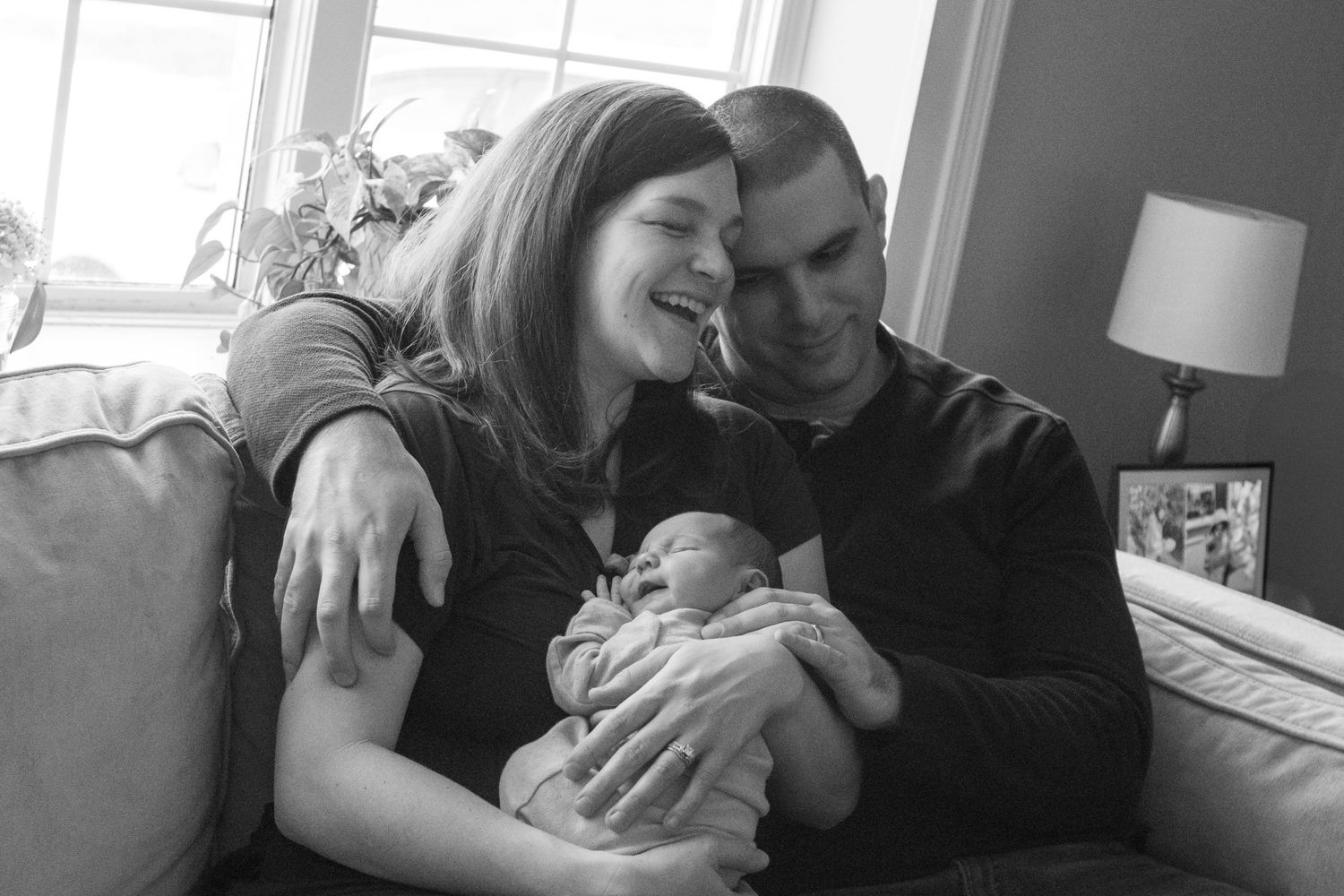 An intimate black and white family moment captured on a cozy couch indoors.