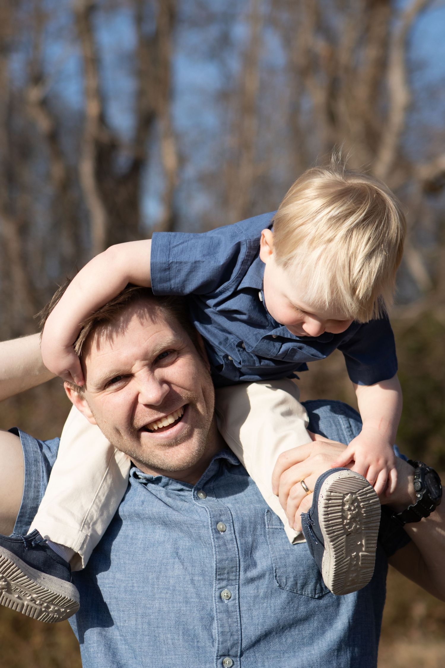 Playful moment with child riding on shoulders in outdoor setting.