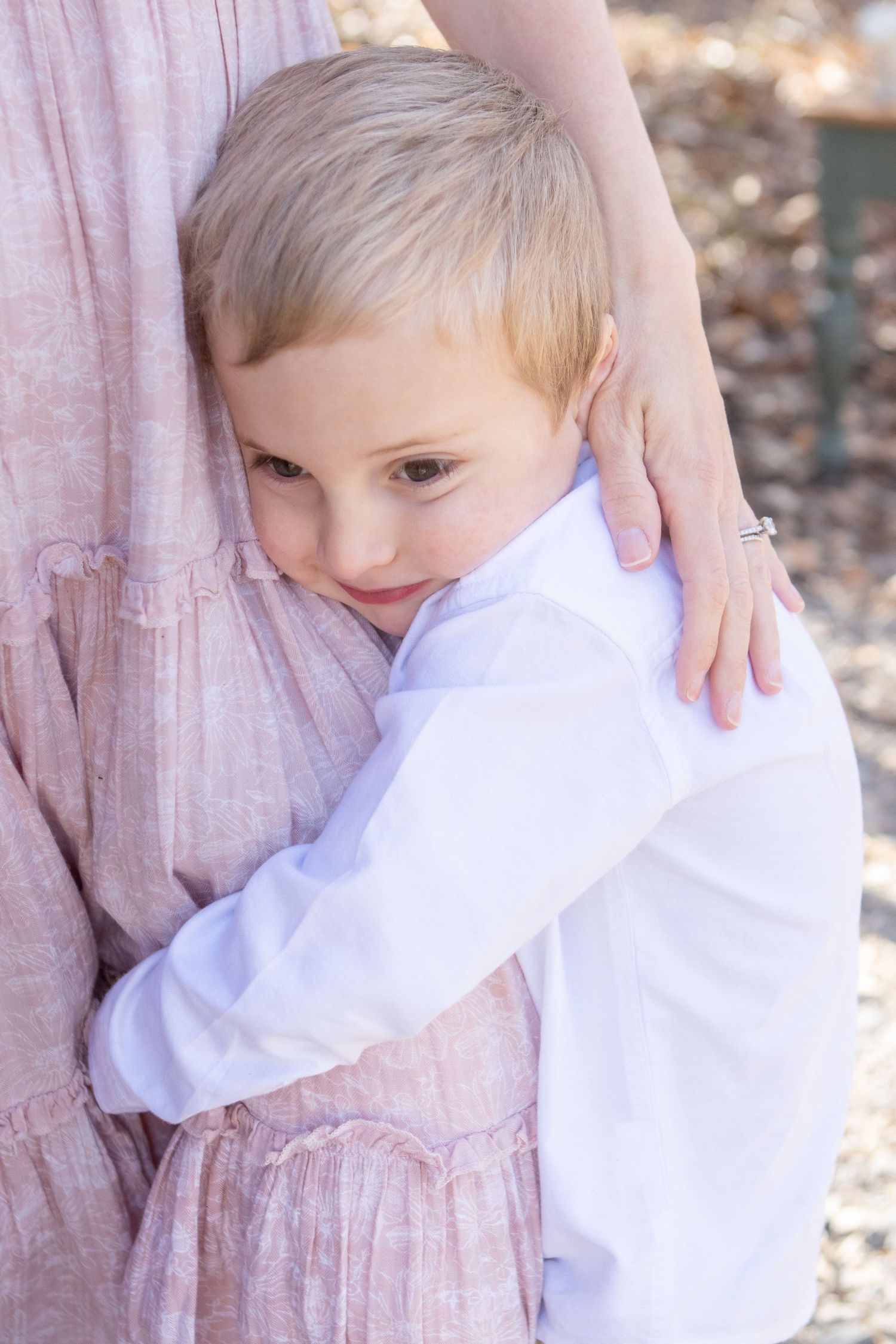 A gentle embrace in pink and white clothing captured against a natural outdoor background.