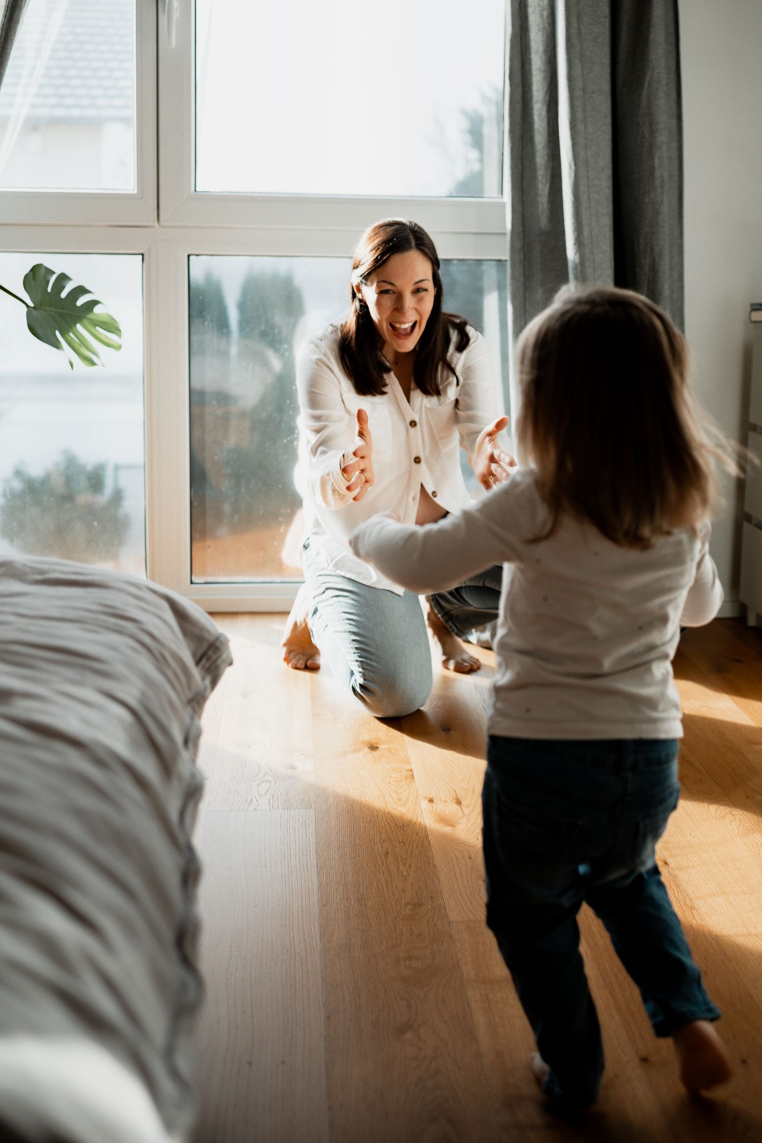 A sequence of photos showing playful interaction between parent and child in sunlit room with white walls and windows.