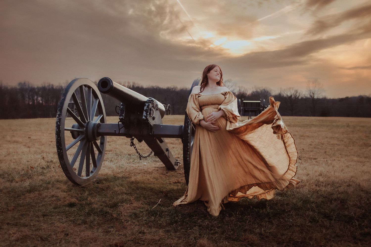 A vintage-style scene with a rustic cannon wheel in a field at sunset, featuring a flowing dress in warm golden light.