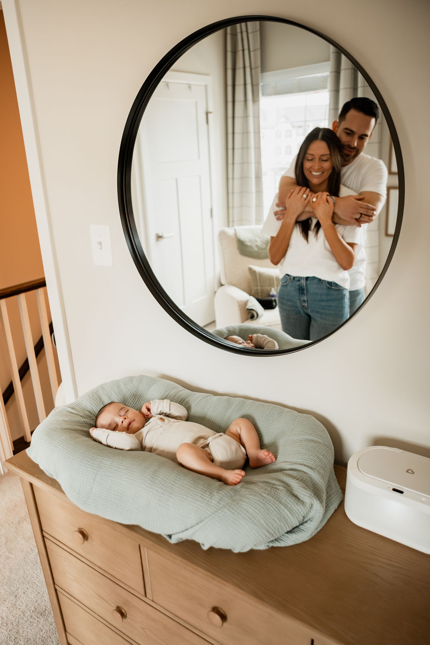 A series of photos shows tender family moments with a newborn baby on a changing table beneath a round mirror.