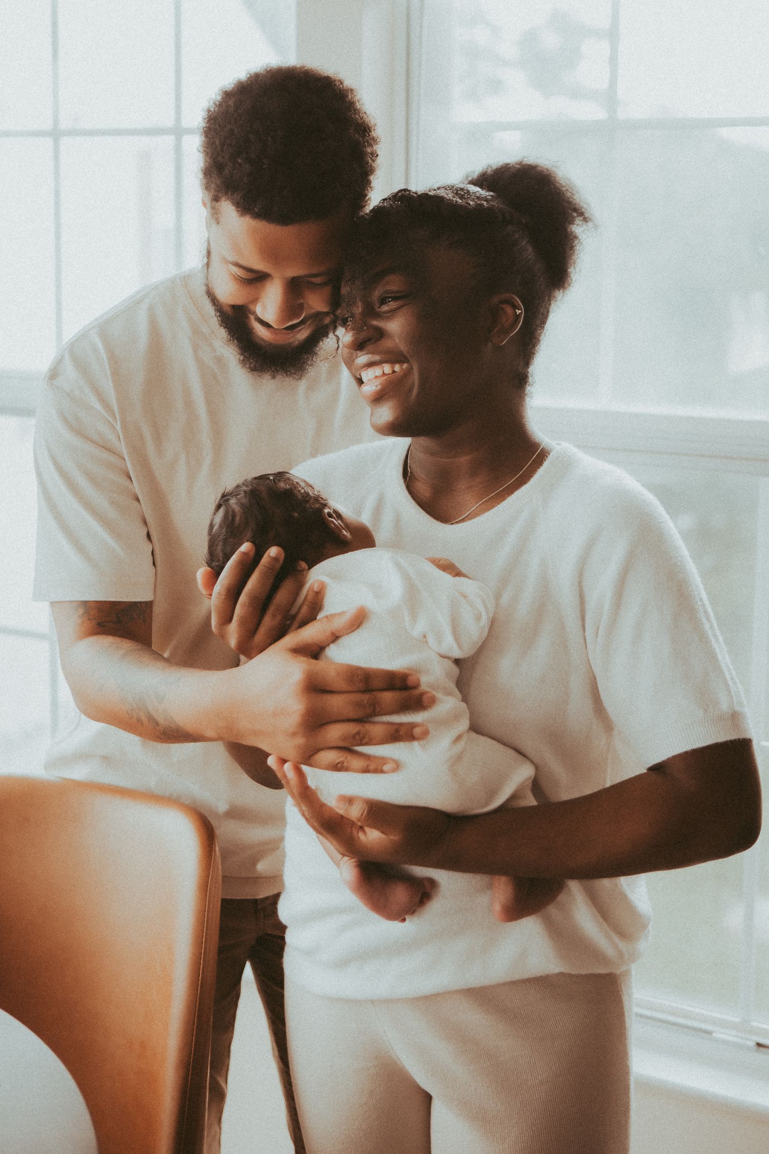 A joyful couple in white t-shirts share a lighthearted moment together while looking at a phone.