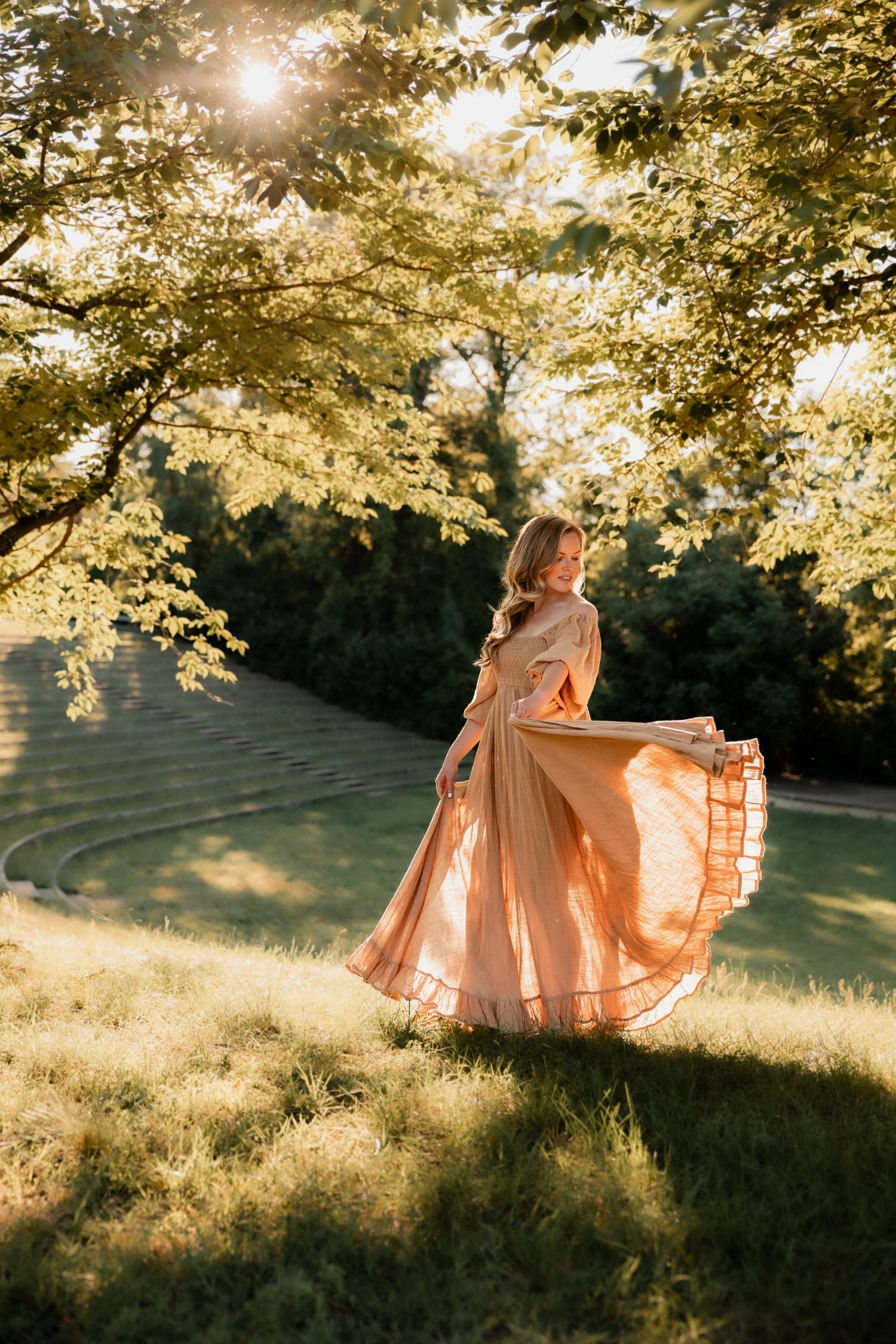 Woman in flowing peach gown twirling in sunlit garden park at golden hour.