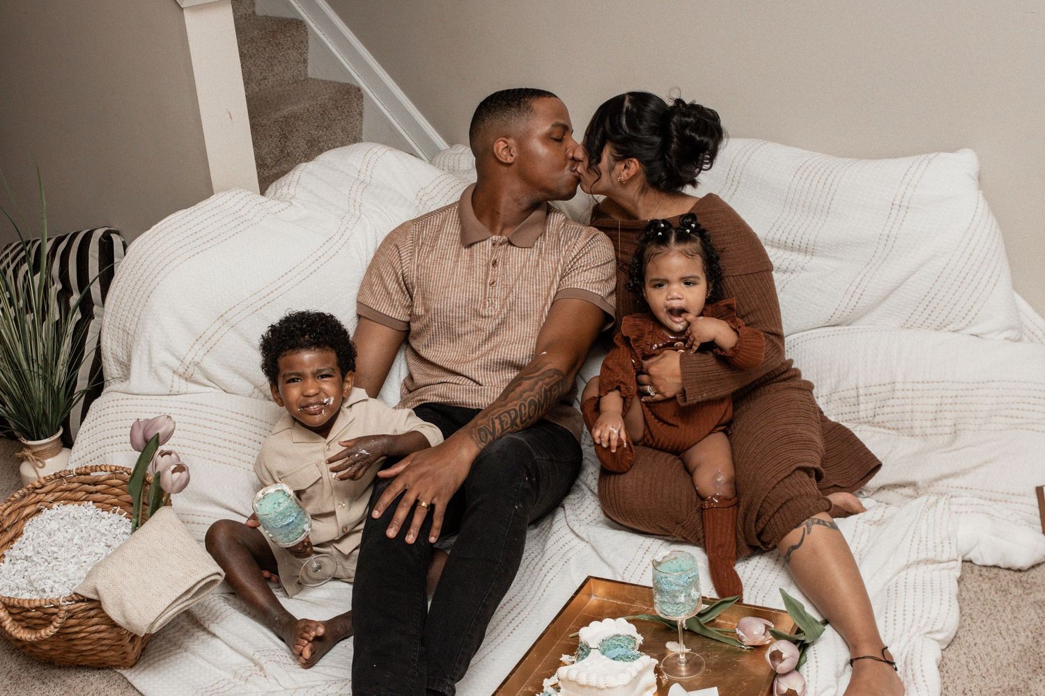 A loving family relaxes together on white bedding while sharing intimate moments at home.