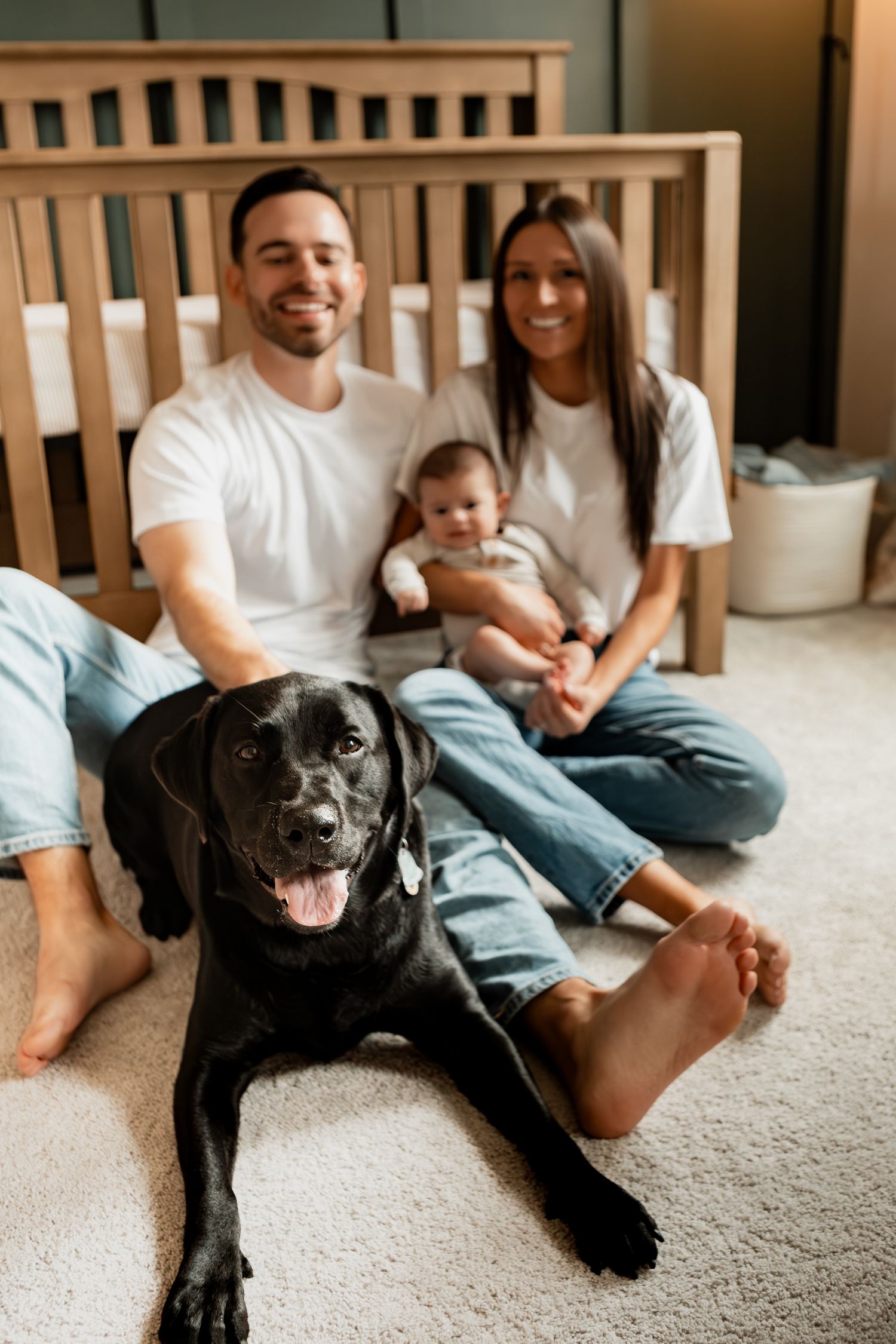 A series of casual indoor photos showing a couple and their black dog lounging together by a bed.