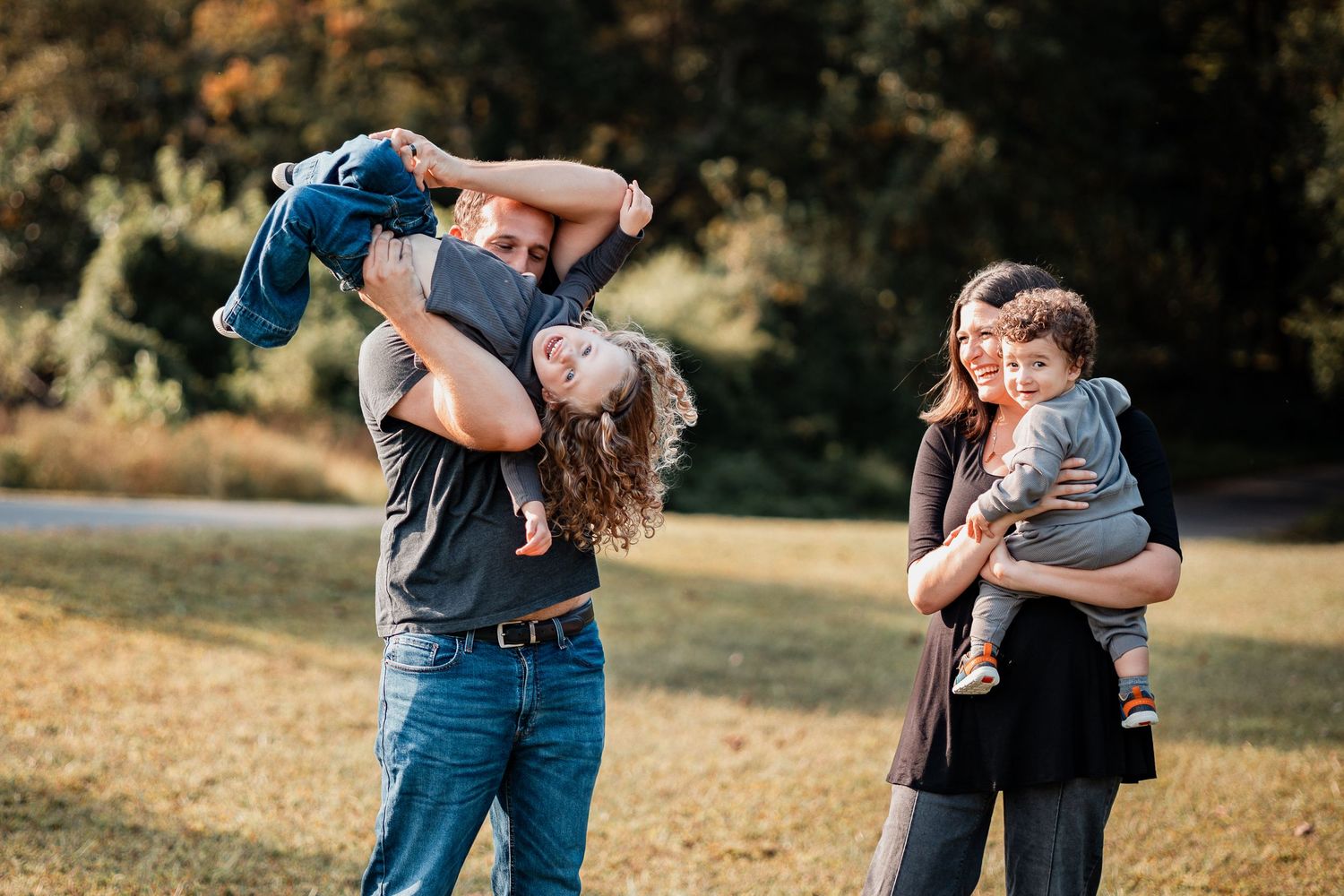 Couple embraces lovingly in a golden autumn field during outdoor photoshoot session at sunset.