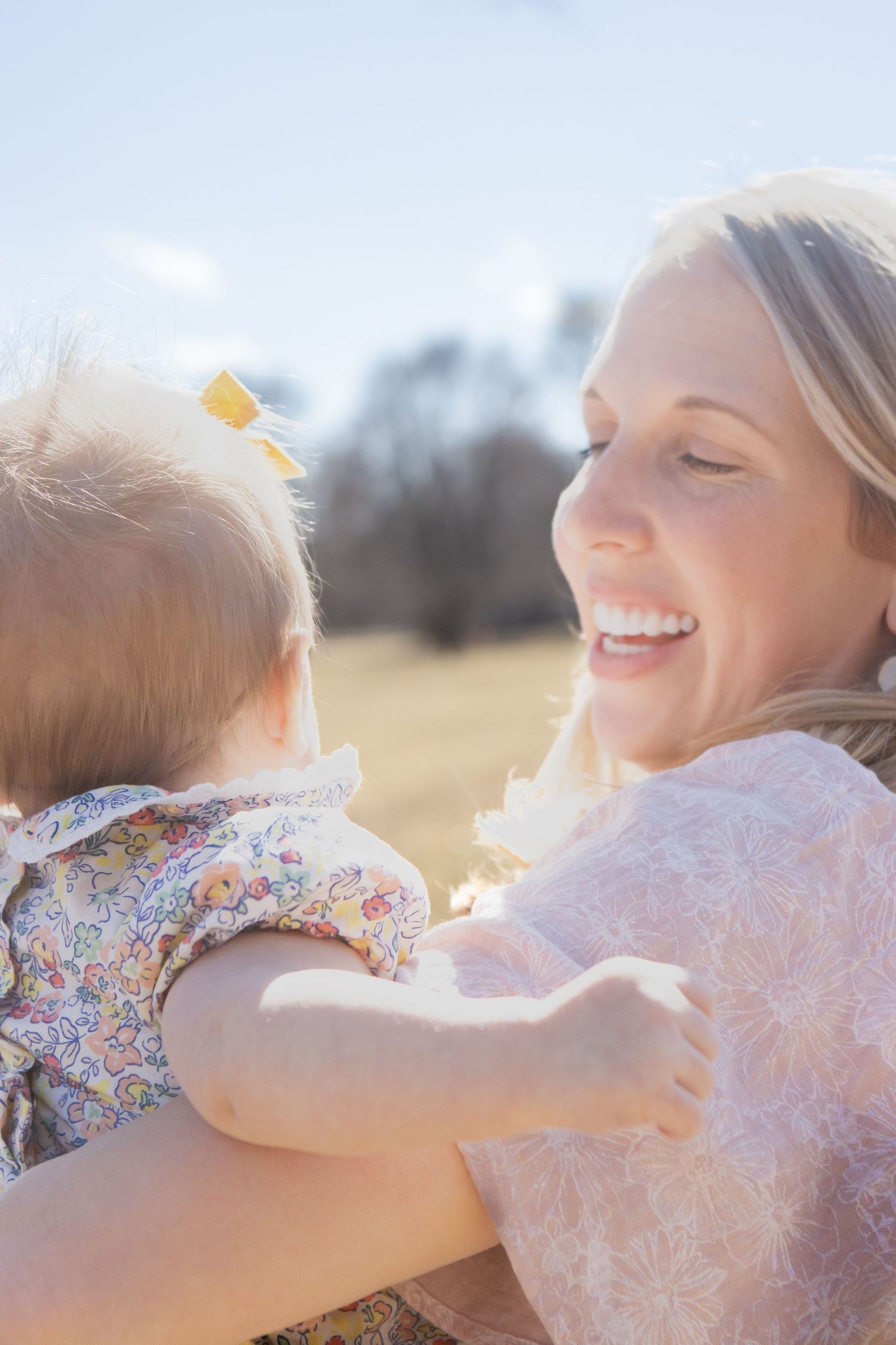 A tender outdoor moment captured in soft sunlight showing an embrace between child and parent.