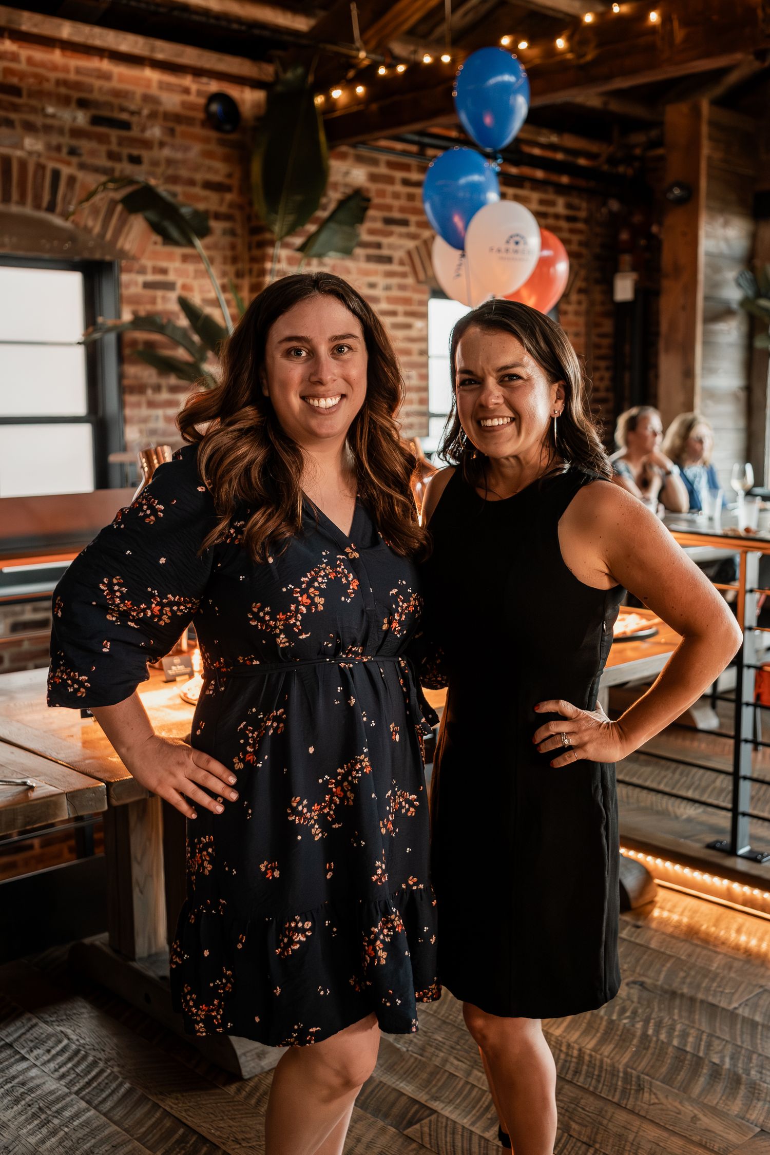 Party celebration in brick-walled venue decorated with blue and white balloons.