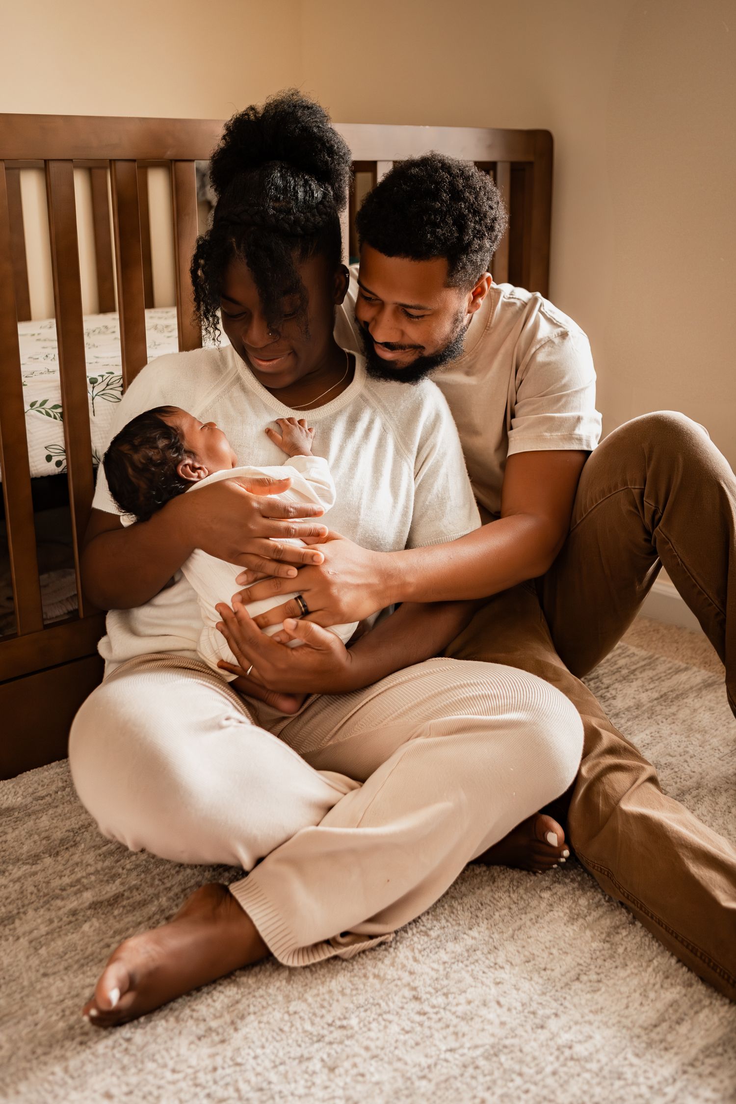 A couple dressed in white lounge together on cream-colored carpet while caring for a baby, shown in sequential photos.