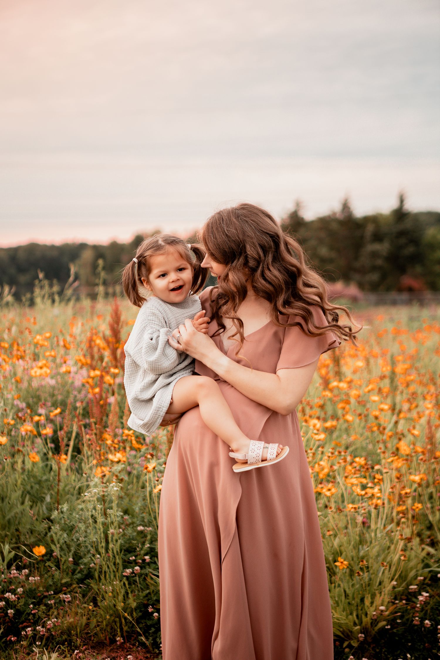 A tender moment shared between two figures in a blooming orange wildflower meadow at sunset.