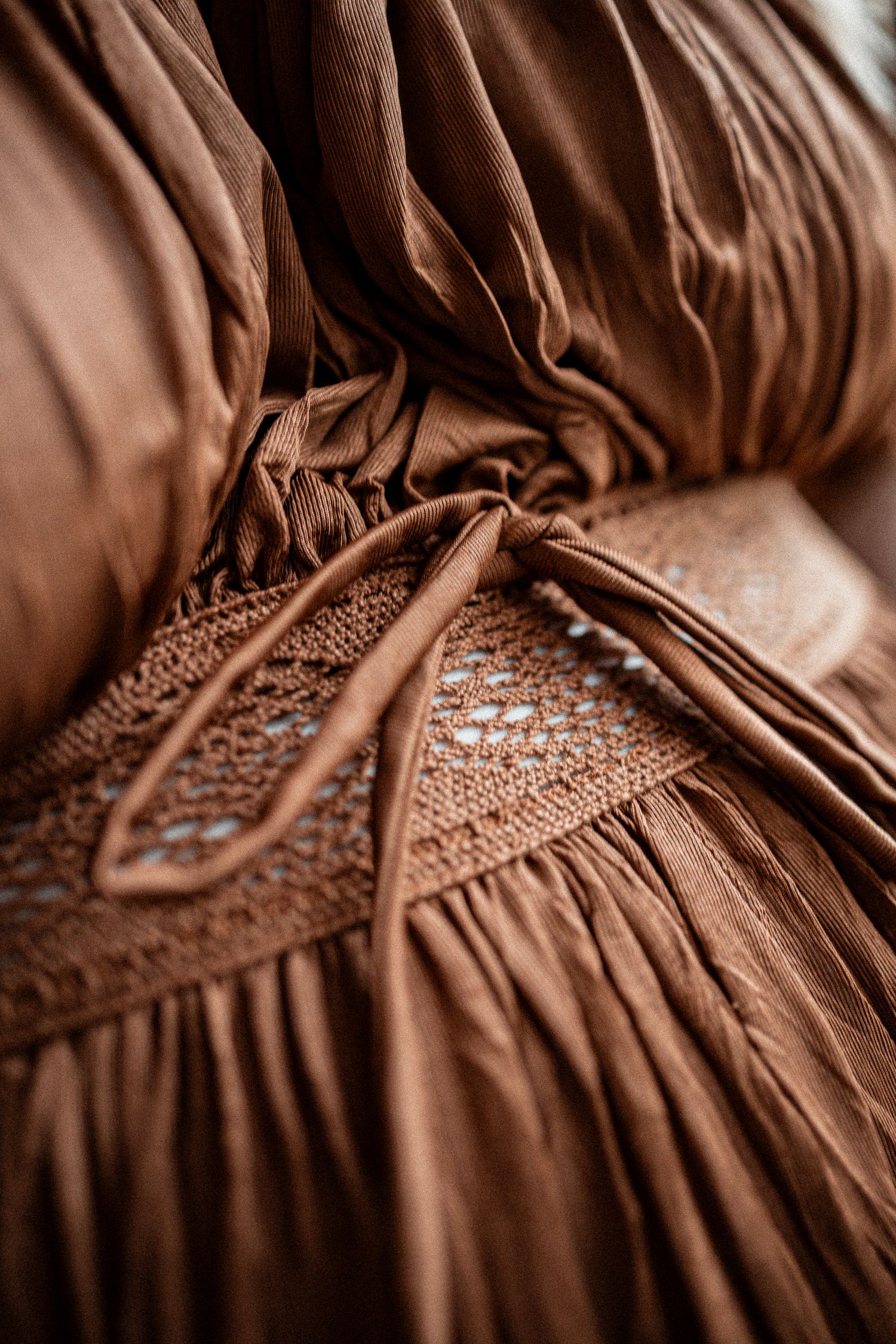 Close-up detail of brown vintage dress showing delicate smocking and gathered fabric texture.