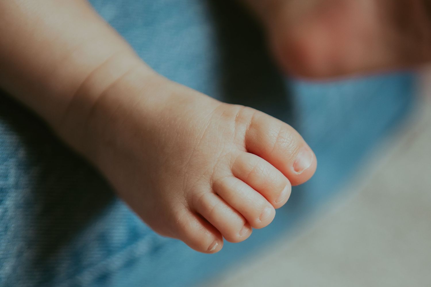Small bare feet of a child walking across a light colored surface in a gentle lighting setup.