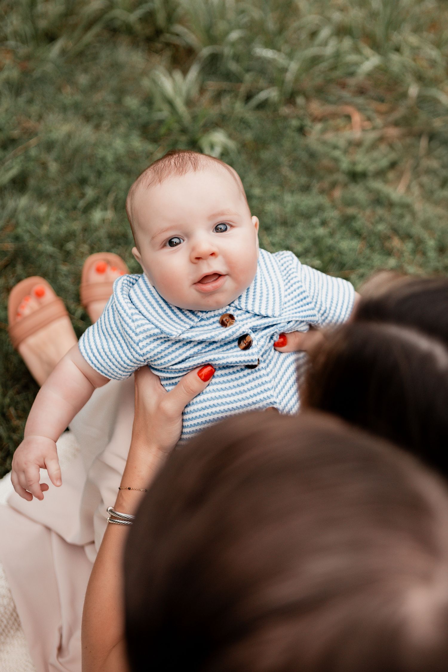 Close-up sequence of baby in striped outfit during outdoor family photoshoot.