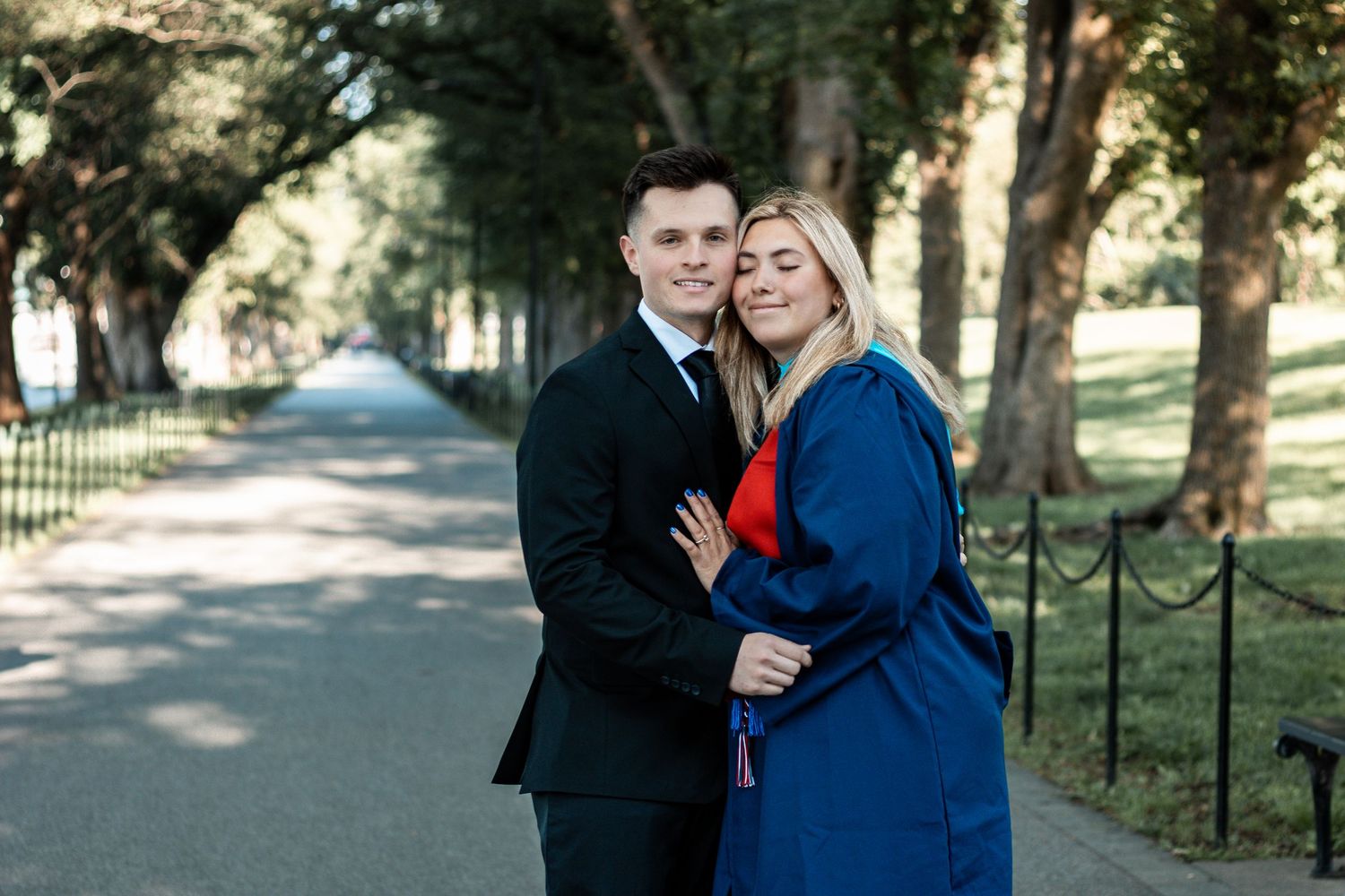 Couple embraces while walking together on a tree-lined path during an autumn photoshoot.