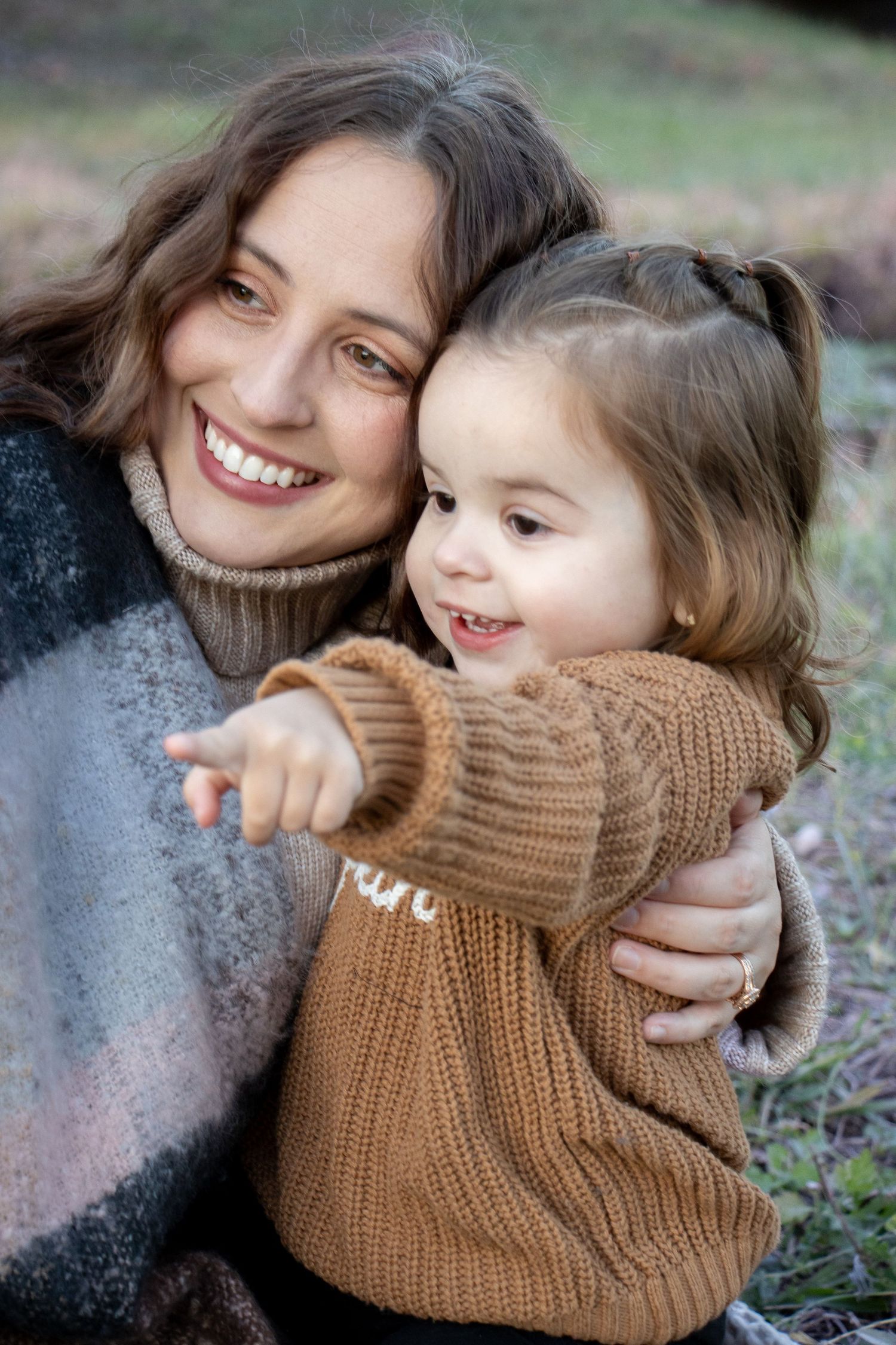 A heartwarming moment shared between parent and child both wearing cozy sweaters outdoors.