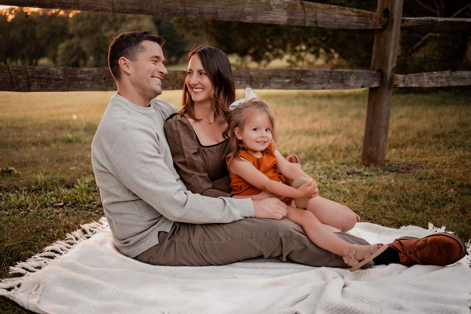 A loving family relaxes together on a blanket in a sun-drenched field during golden hour.
