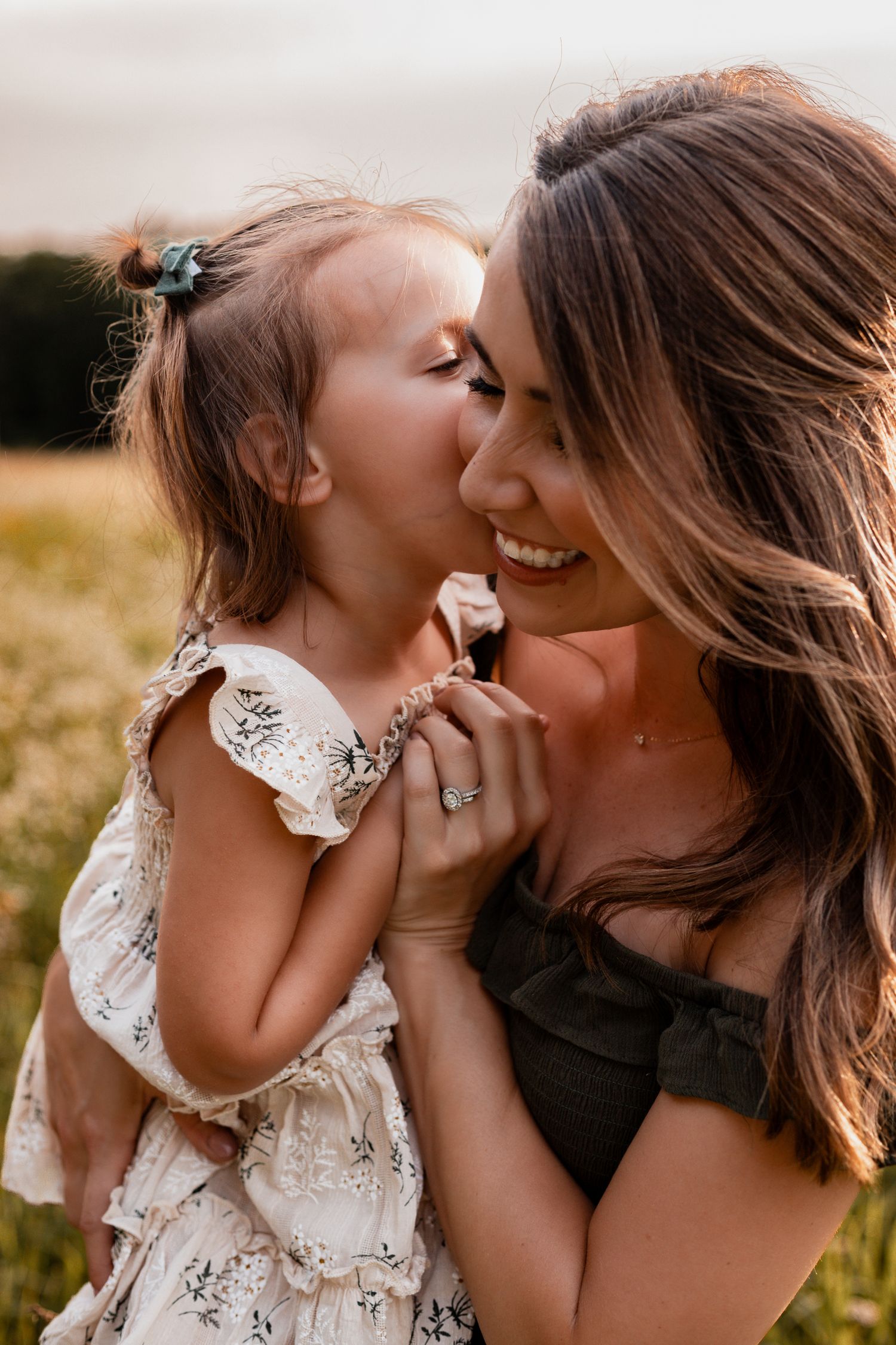 A tender moment between parent and child playing together in a golden field at sunset.