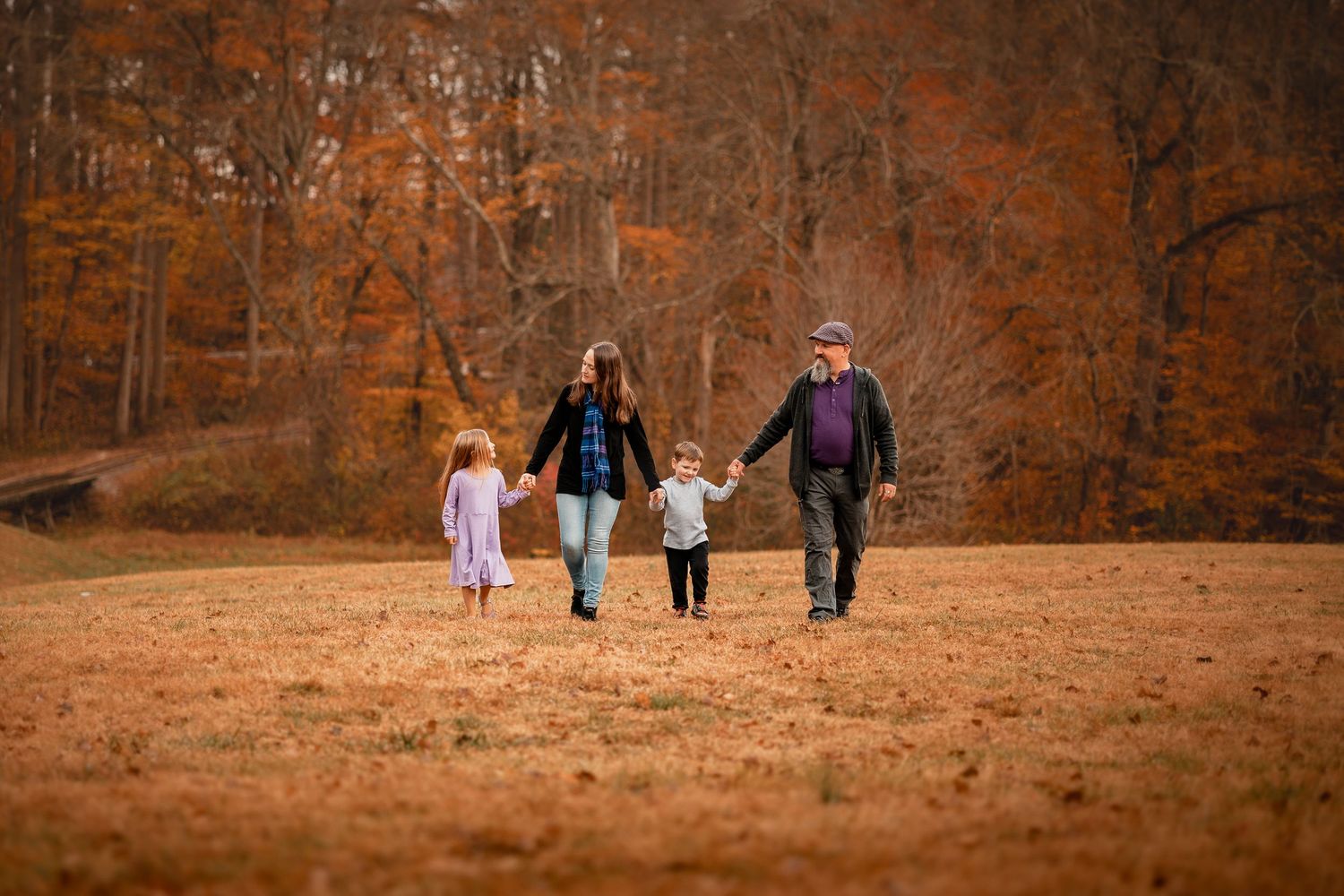 Silhouettes of people walking together against warm autumn forest backdrop.