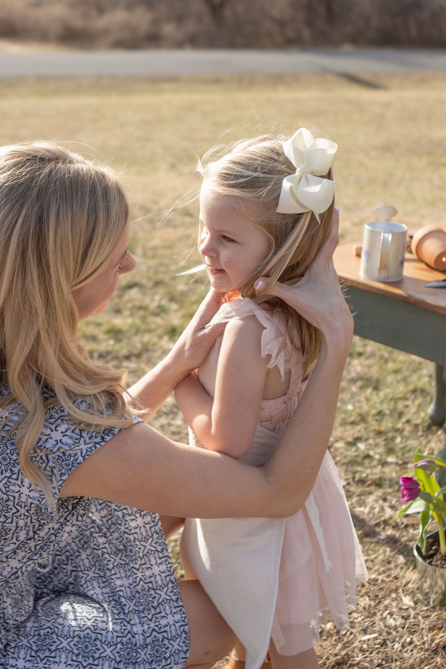 Parent and child in spring meadow sharing tender moment during outdoor gardening activity.