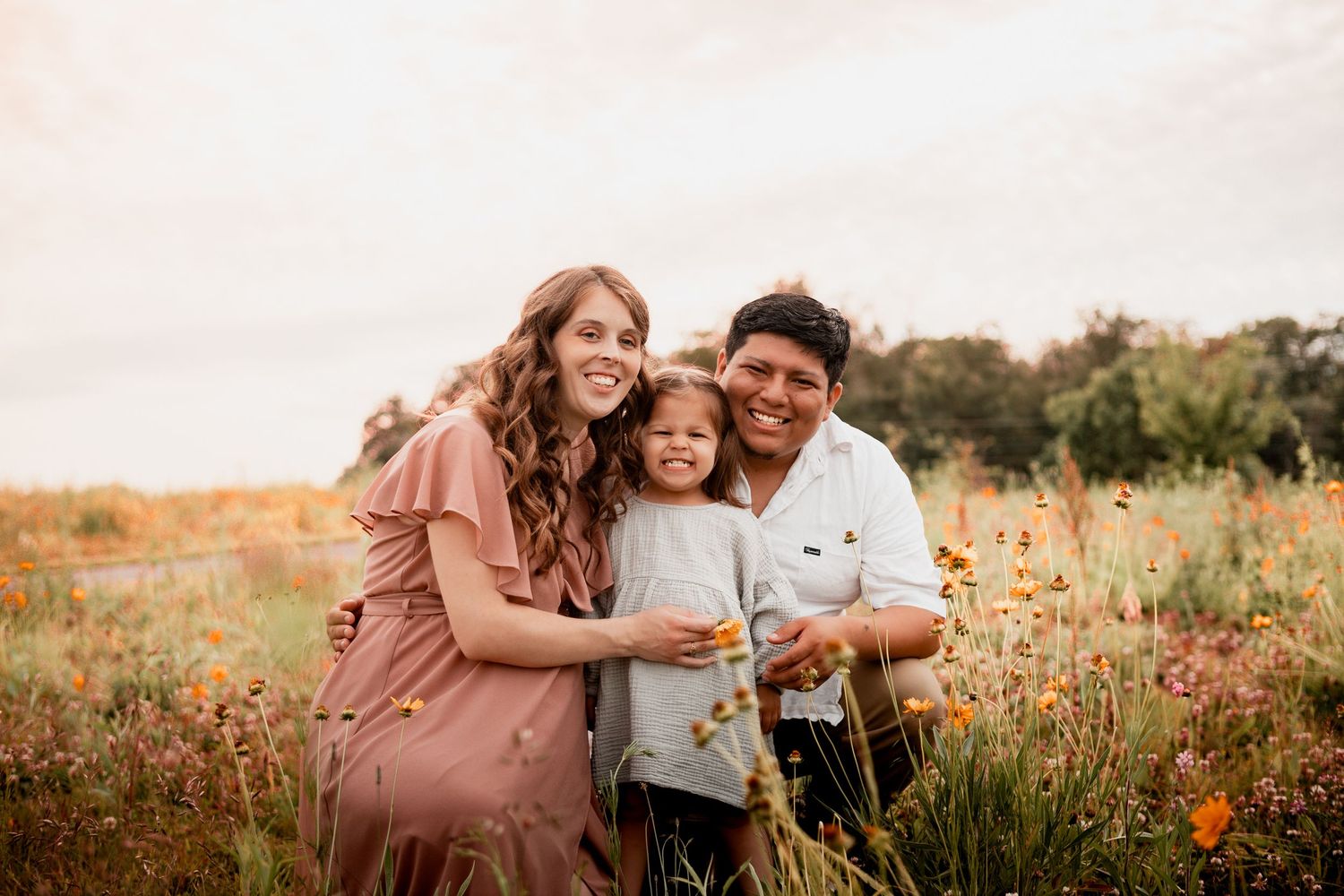 People enjoying a tender moment together while sitting in a vibrant orange wildflower field at sunset.