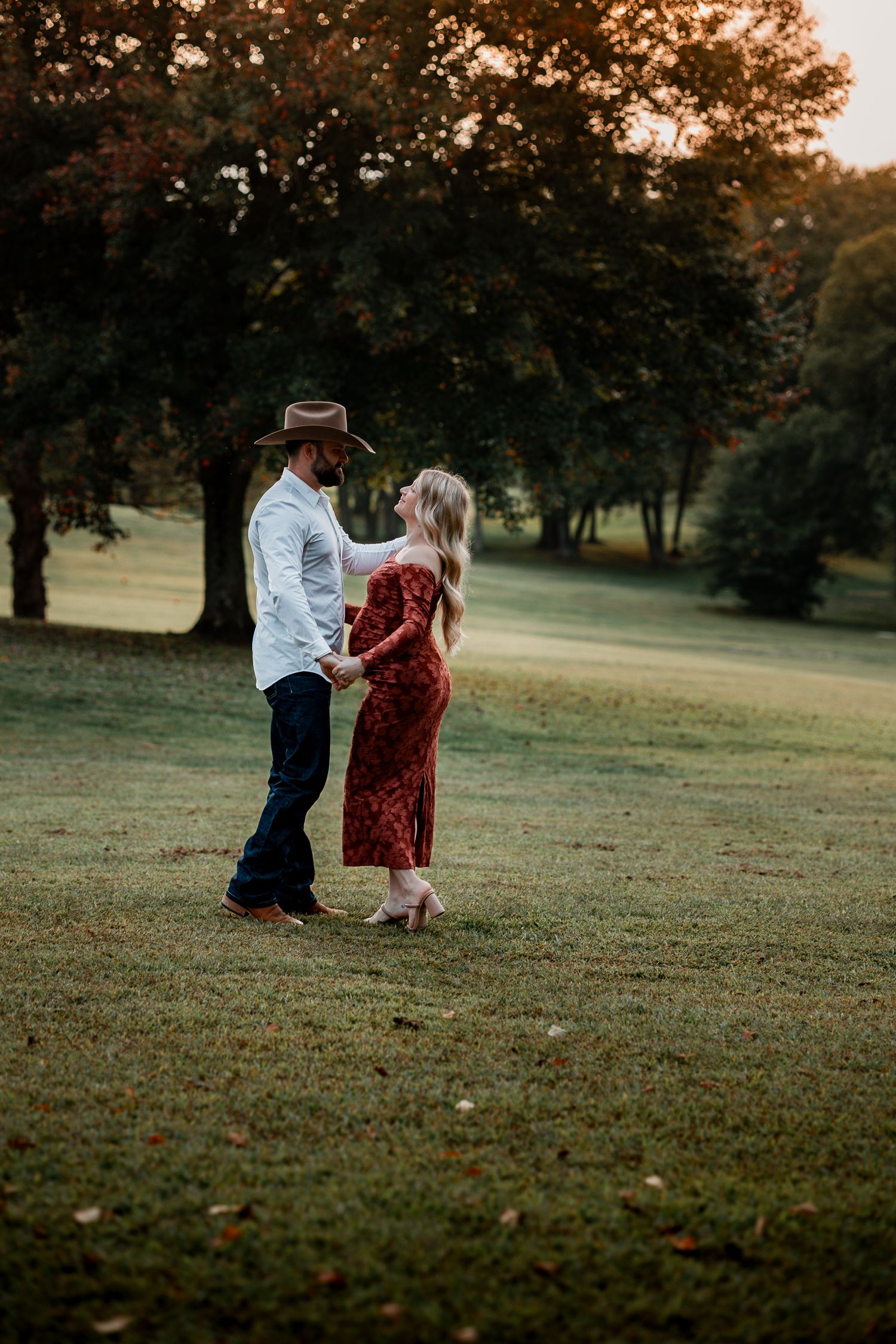 A couple dances together in a park during golden hour.