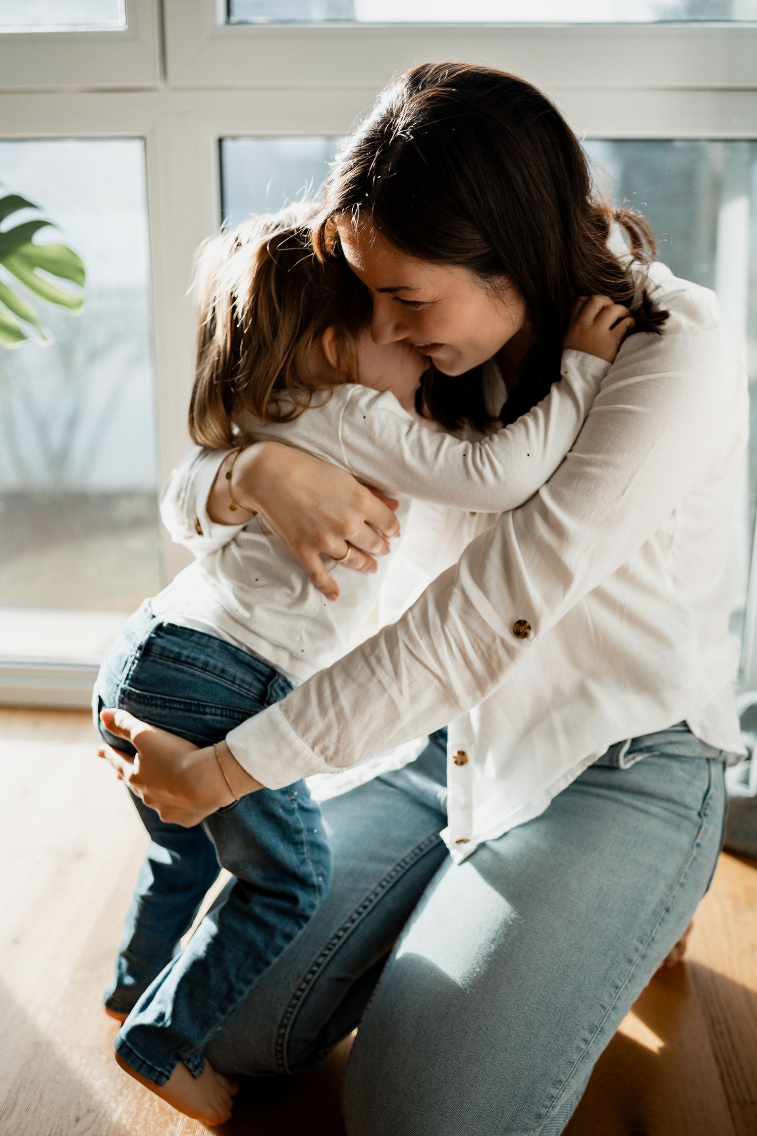 Intimate family bonding moment showing parent and child embracing on a sunny afternoon at home.