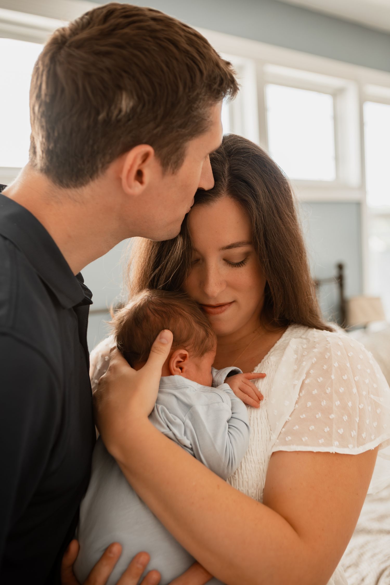 A tender family moment showing parents holding and cuddling their newborn baby.