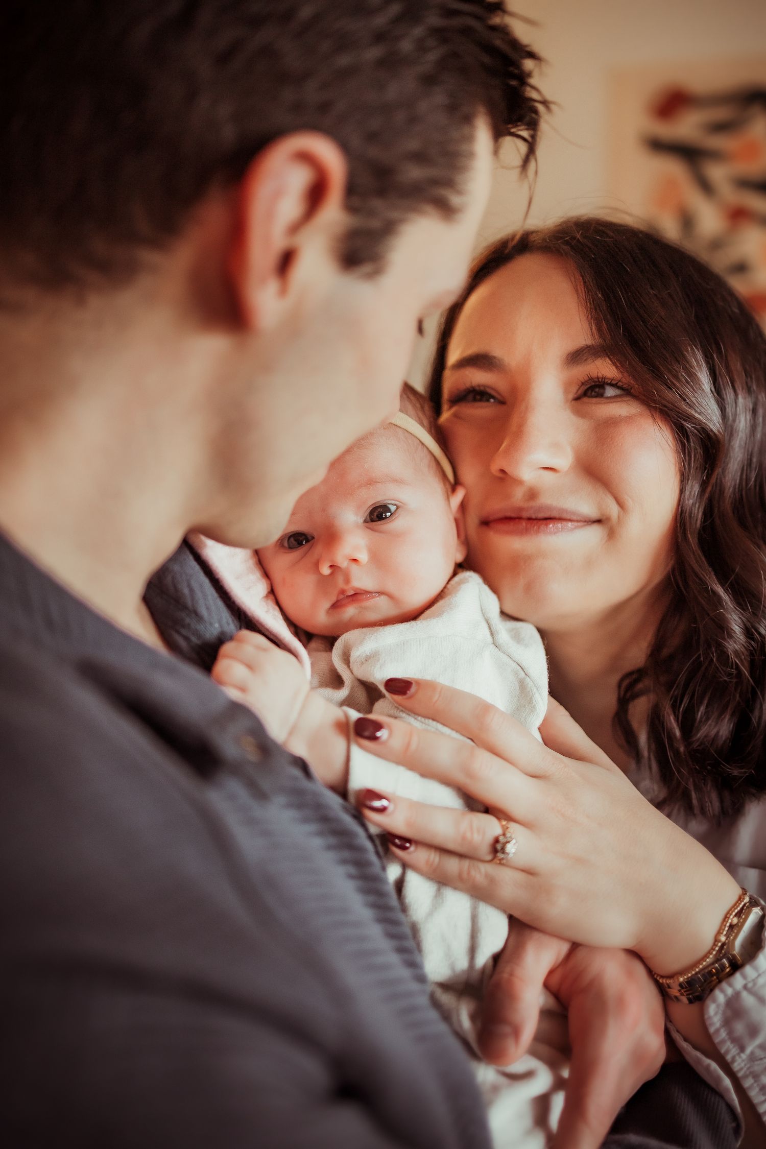 A series of intimate close-up shots showing tender family moments with a baby in a white outfit.
