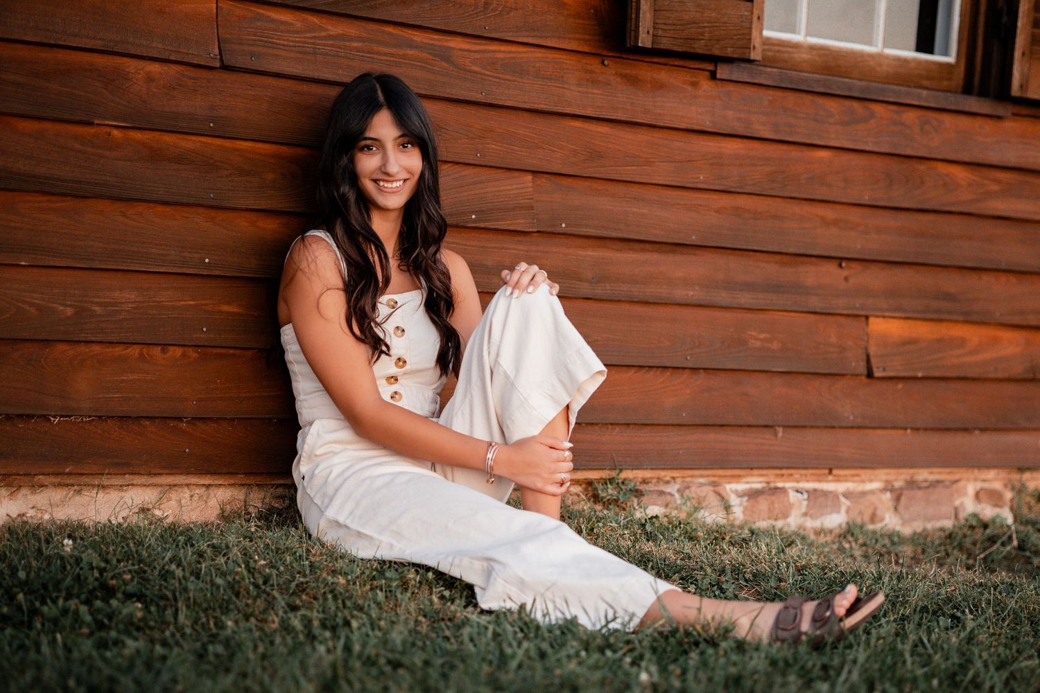 Casual portrait session against weathered wood siding in white summer attire.