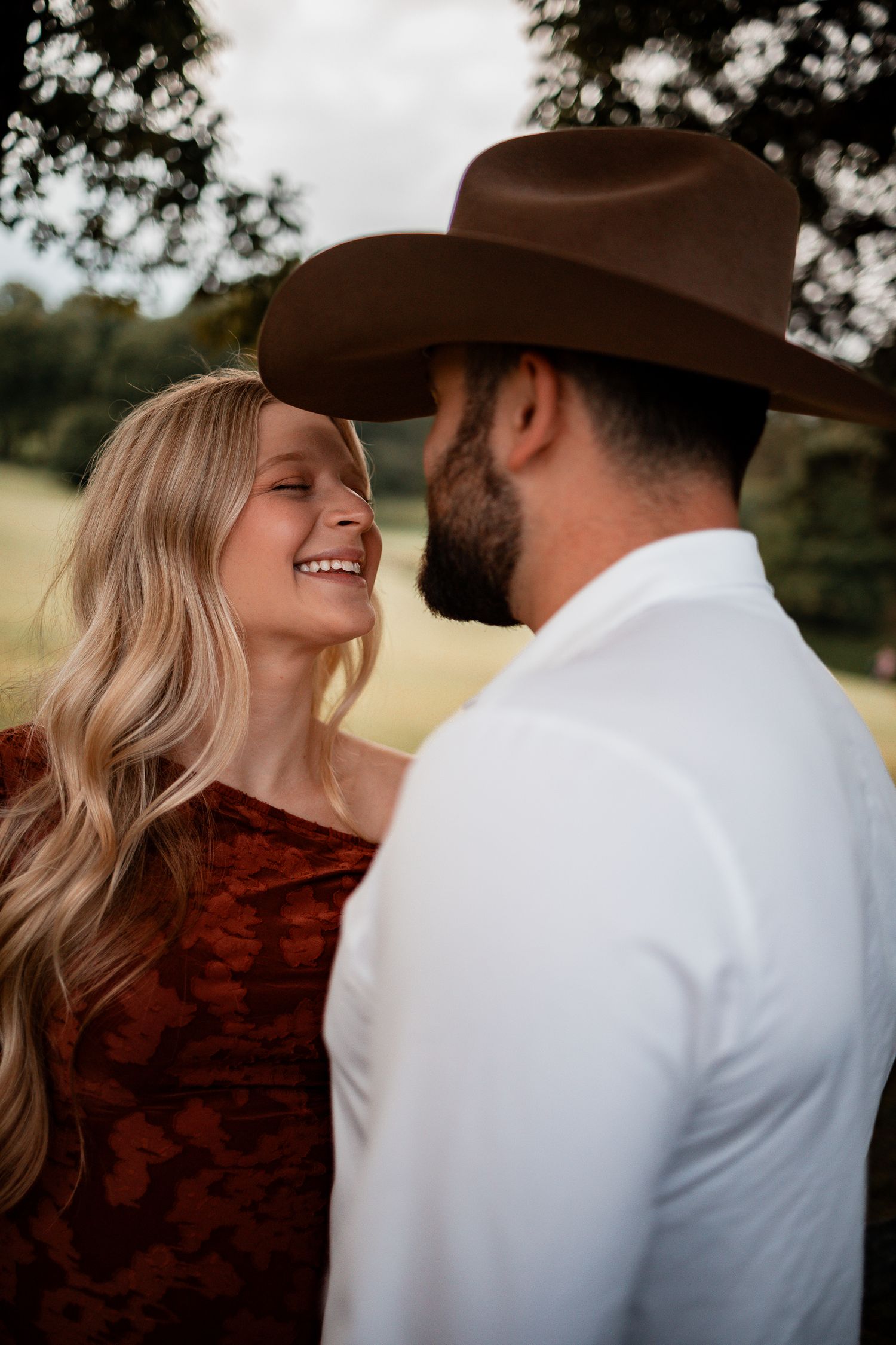 A couple shares an intimate moment outdoors wearing contrasting rust and white outfits.