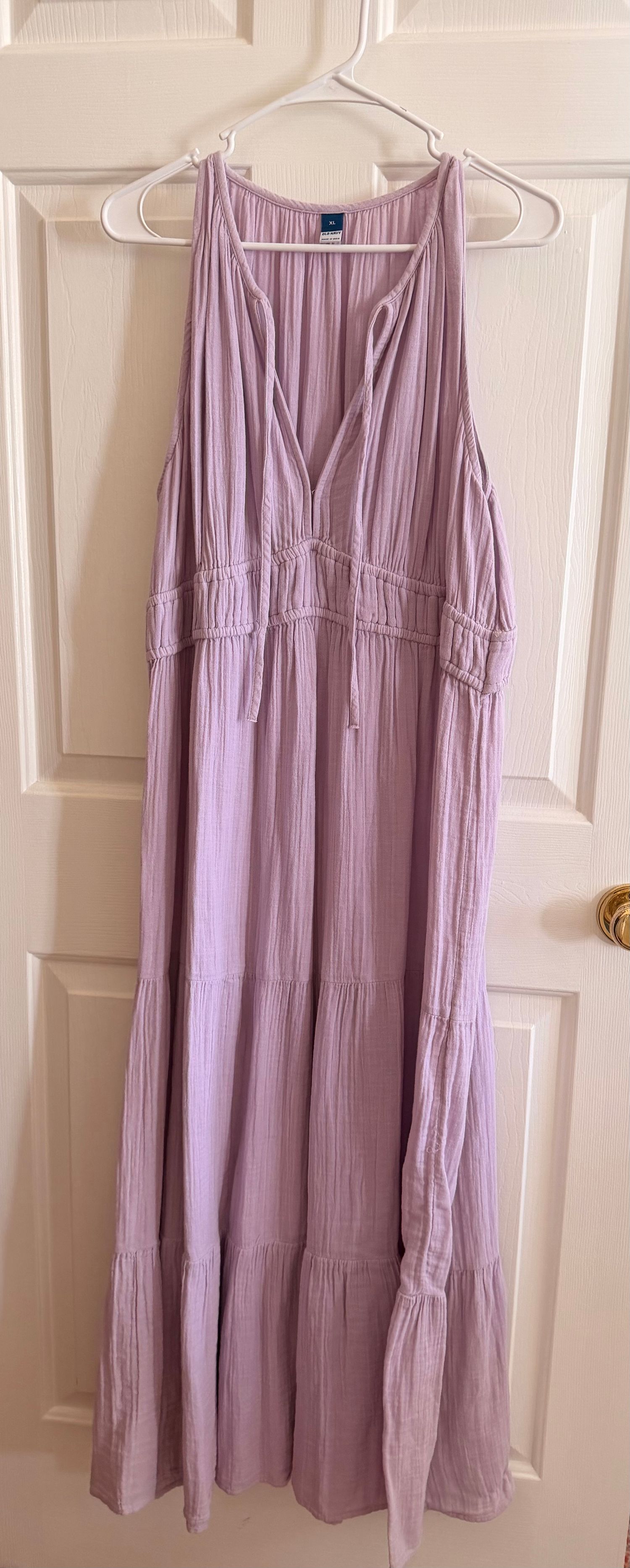 Lavender sleeveless tiered maxi dress with V-neck and ruched waist detail, hanging on a white door hanger.