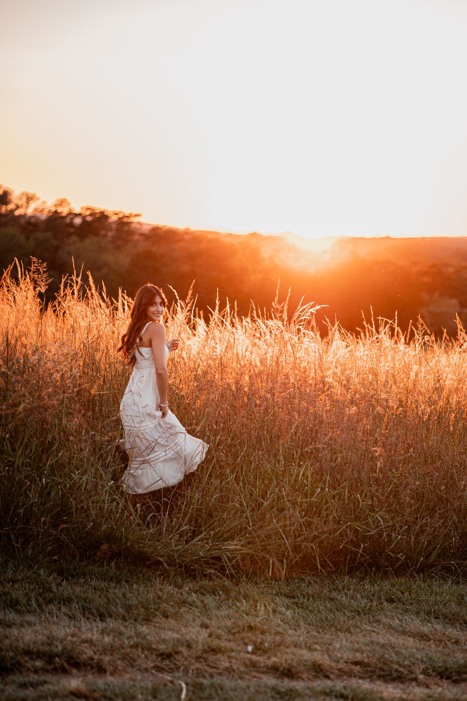 Silhouette photo of white dress flowing in golden field during sunset.