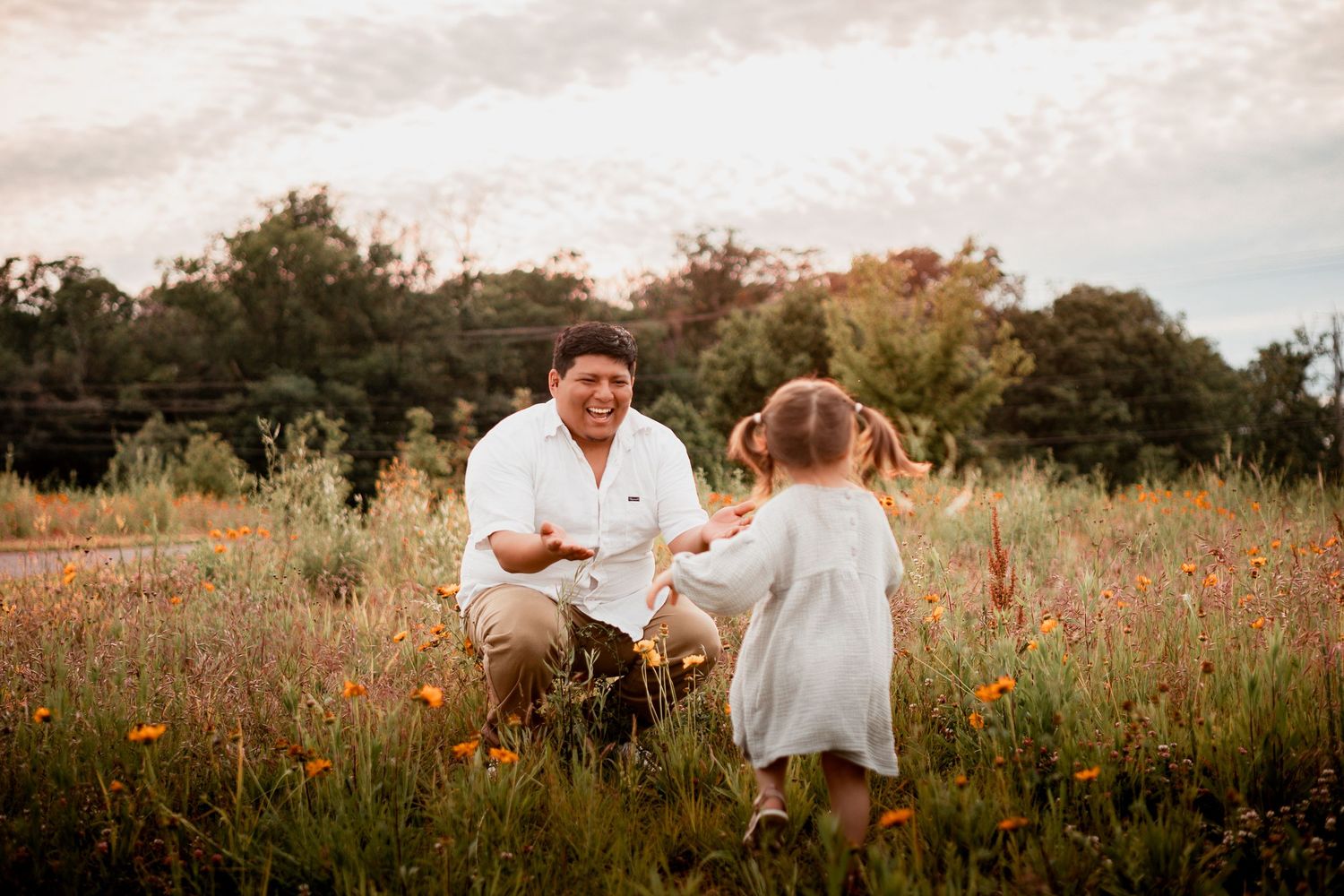 A tender moment shared between two people amongst wildflowers in a summer meadow at golden hour.