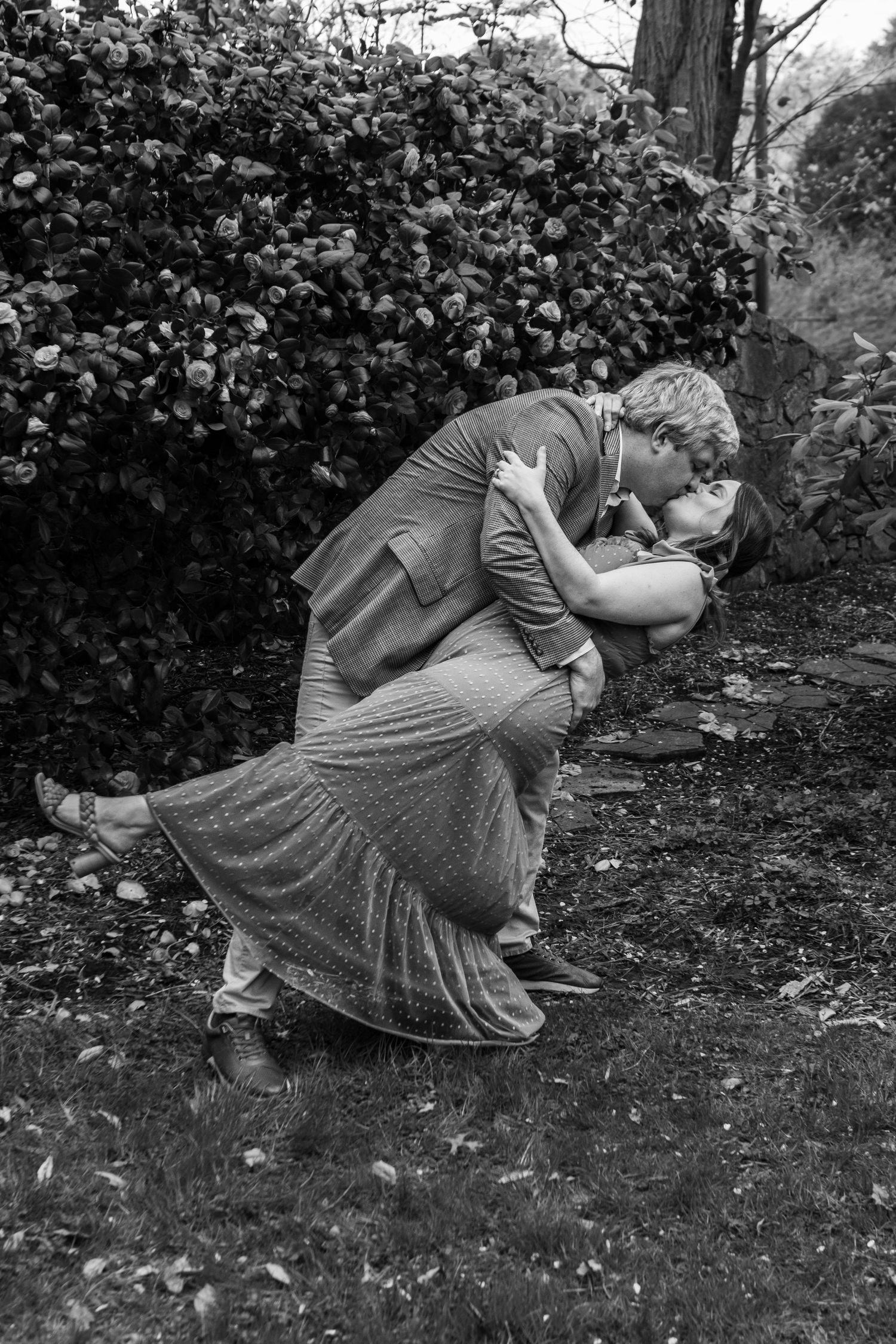 A sequence of black and white photographs shows a person in a dress crouching and curling into a ball on the ground.