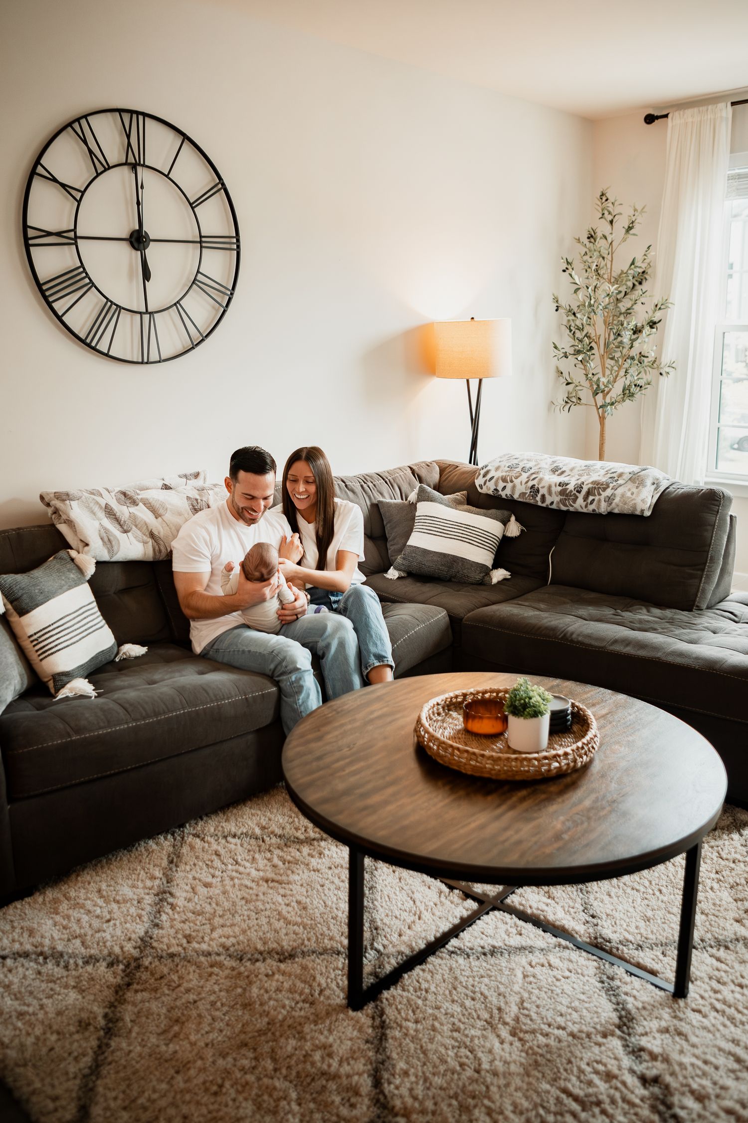 Stylish living room with black sofa, clock decor, plush rug and family relaxing together on a cozy afternoon.