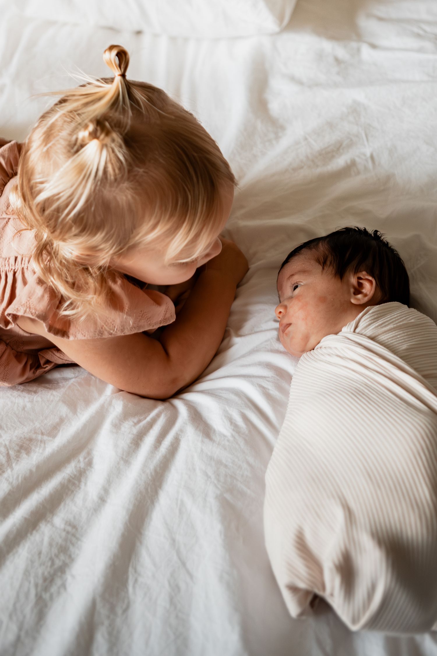 A baby sleeping peacefully in white bedding, shown in multiple angles while wearing a white outfit.