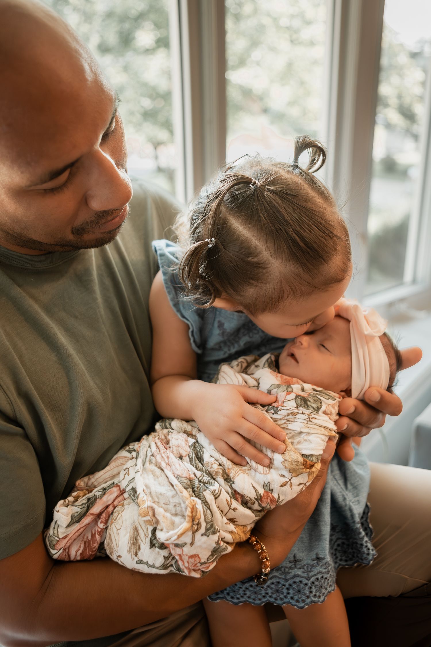 A tender parenting moment shows a gentle embrace and kiss between adult and child in warm natural lighting.