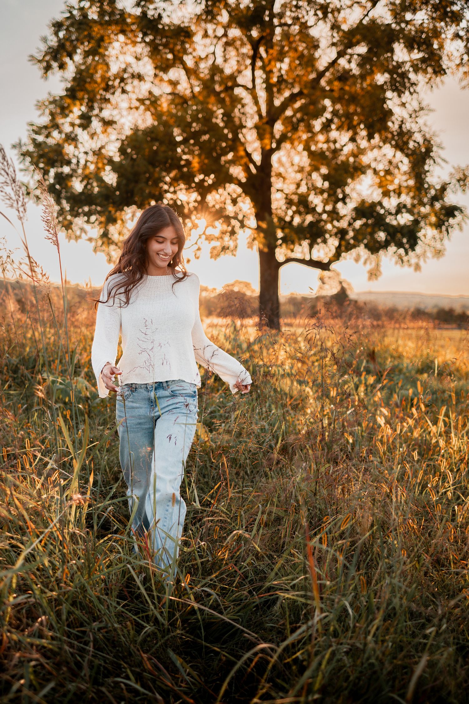 A casual autumn photoshoot in a field with tall grass and trees at golden hour.