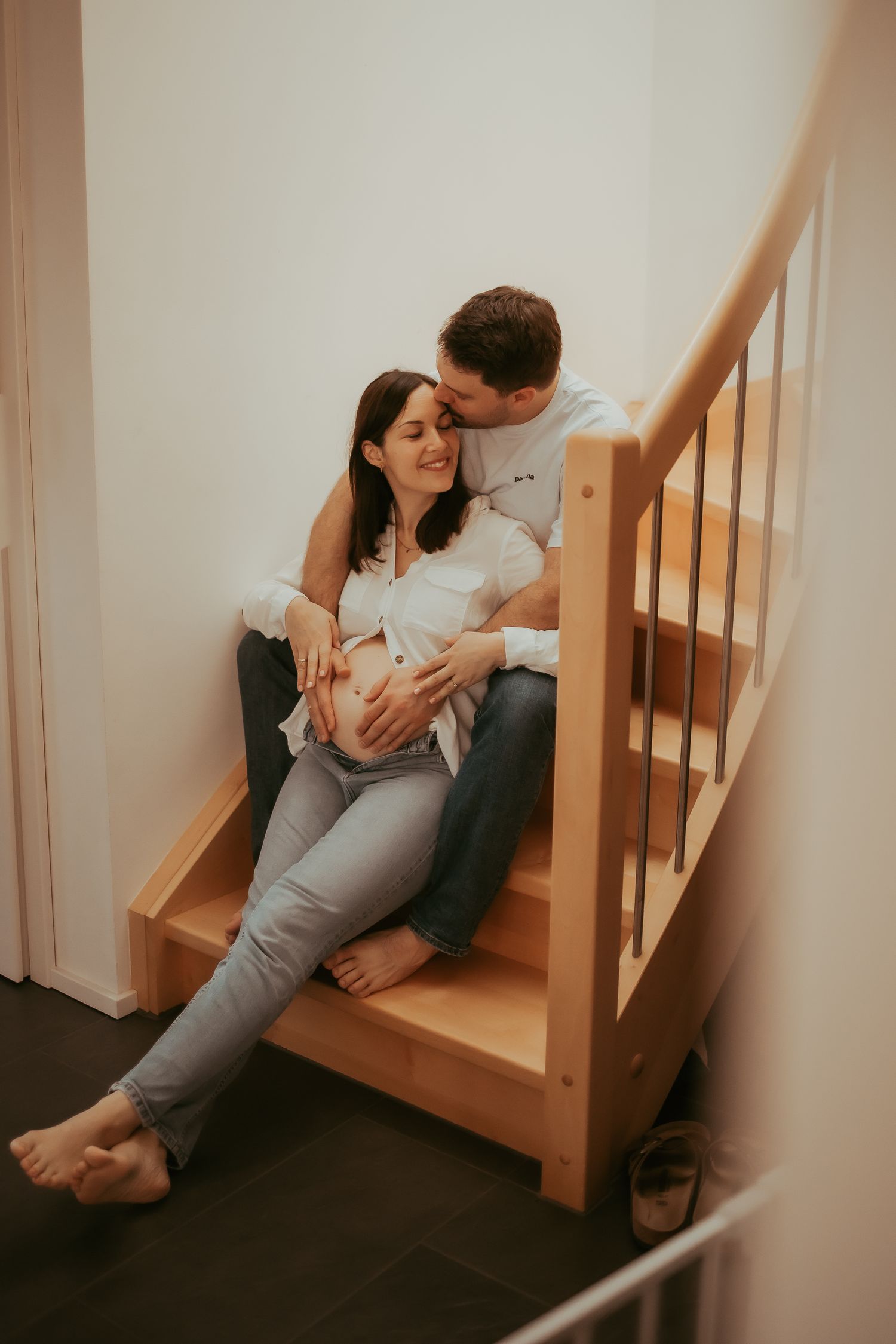 A tender moment showing a couple sitting together on stairs during pregnancy.