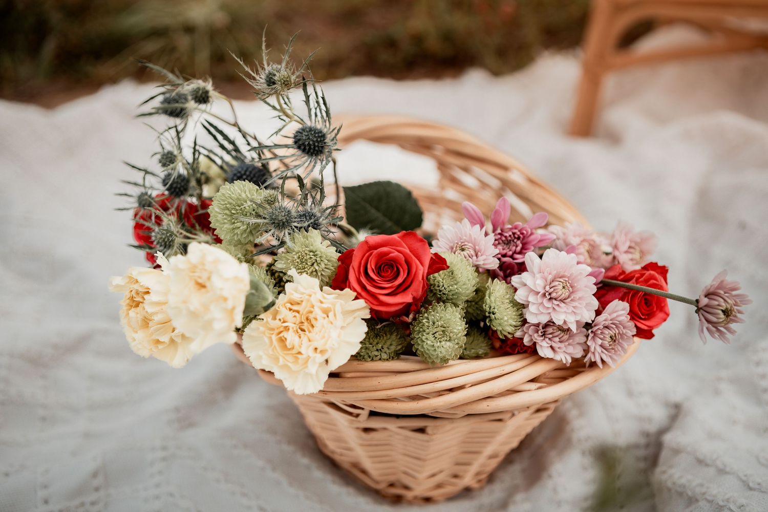Beautiful floral arrangement featuring peach, red, and pink blooms with greenery in a natural woven basket.