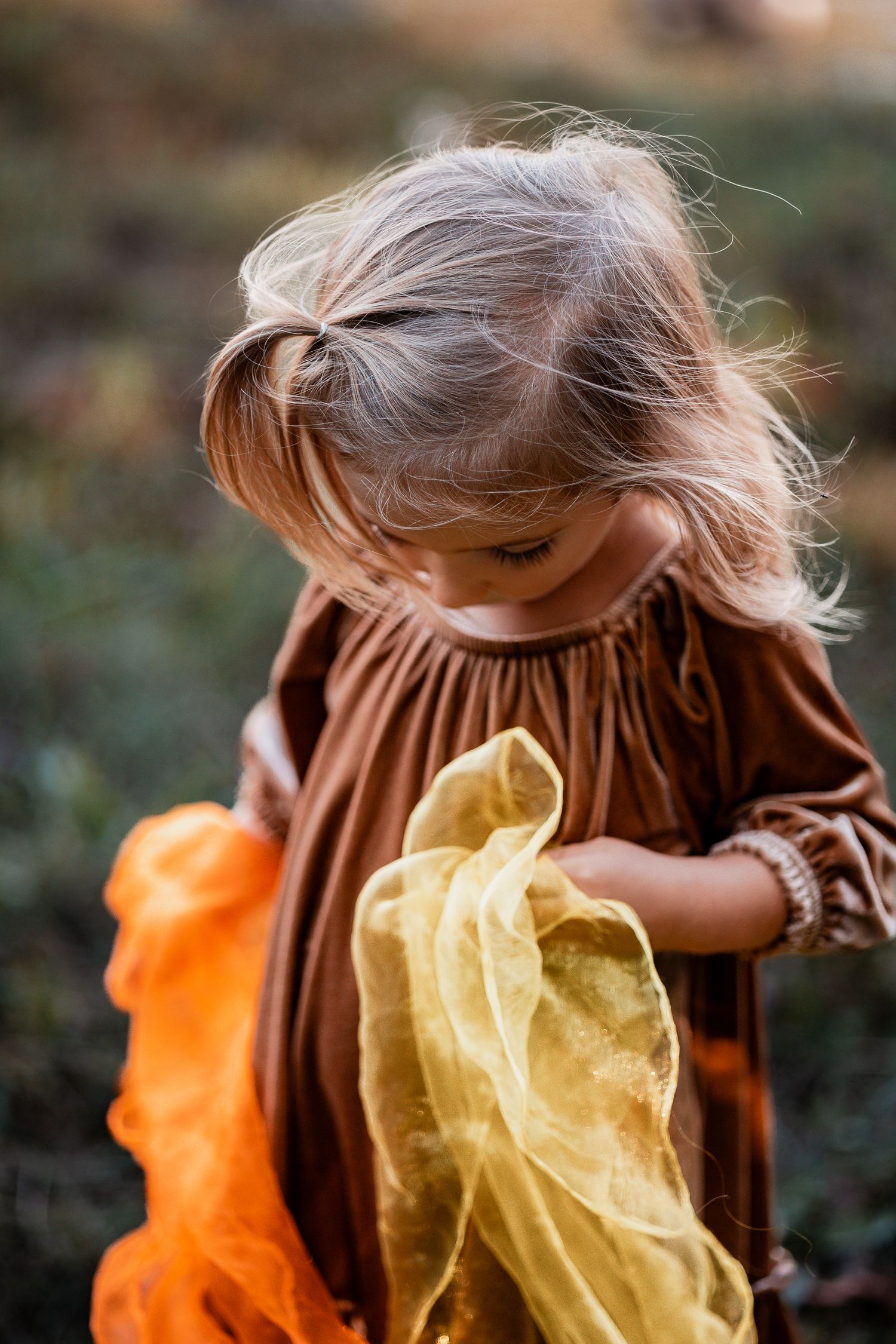 Flowing yellow and orange sheer fabric creates an ethereal movement effect against a dark background.