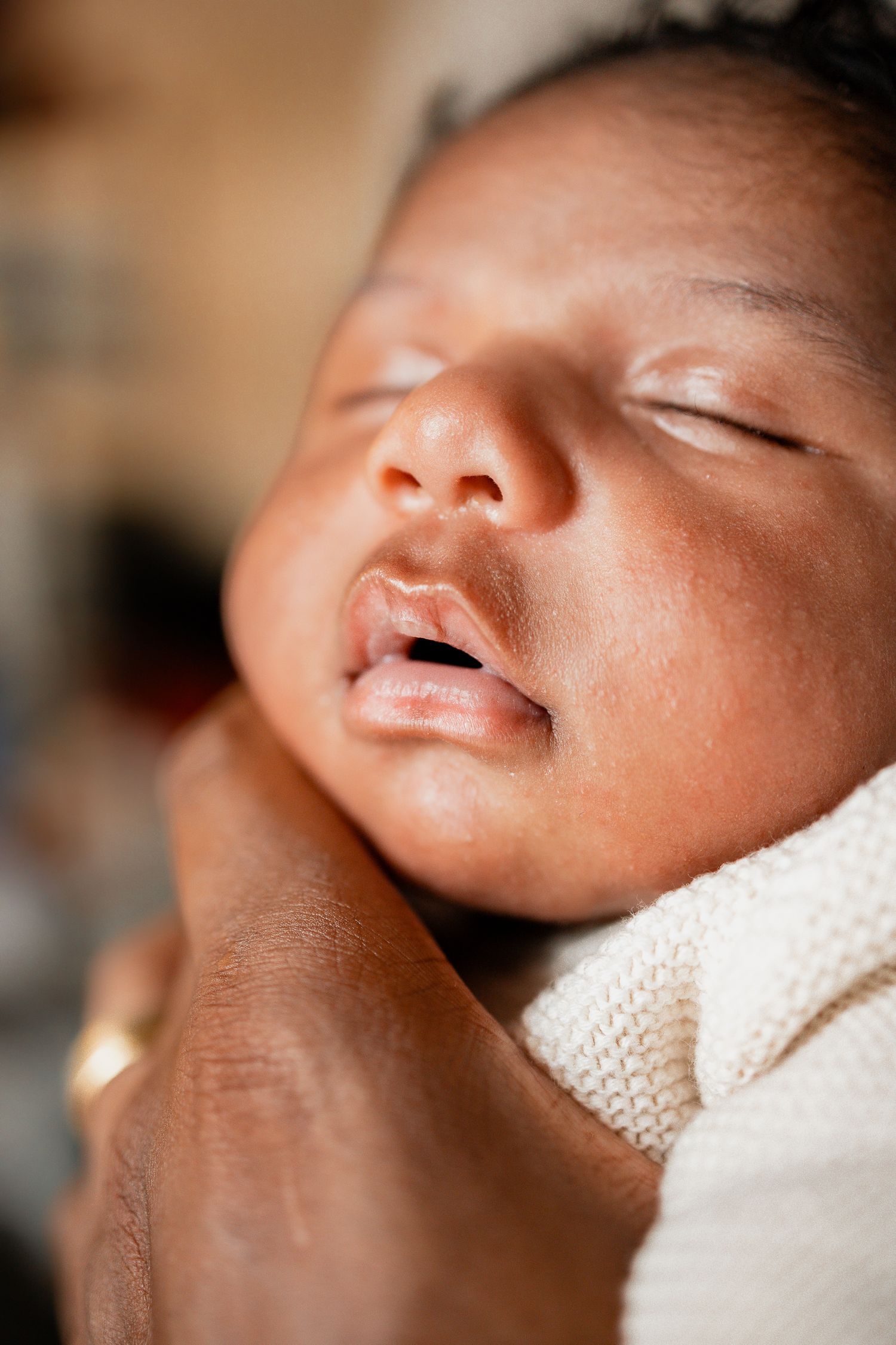Close-up photo series showing a sleeping newborn baby's peaceful face wrapped in a white blanket.
