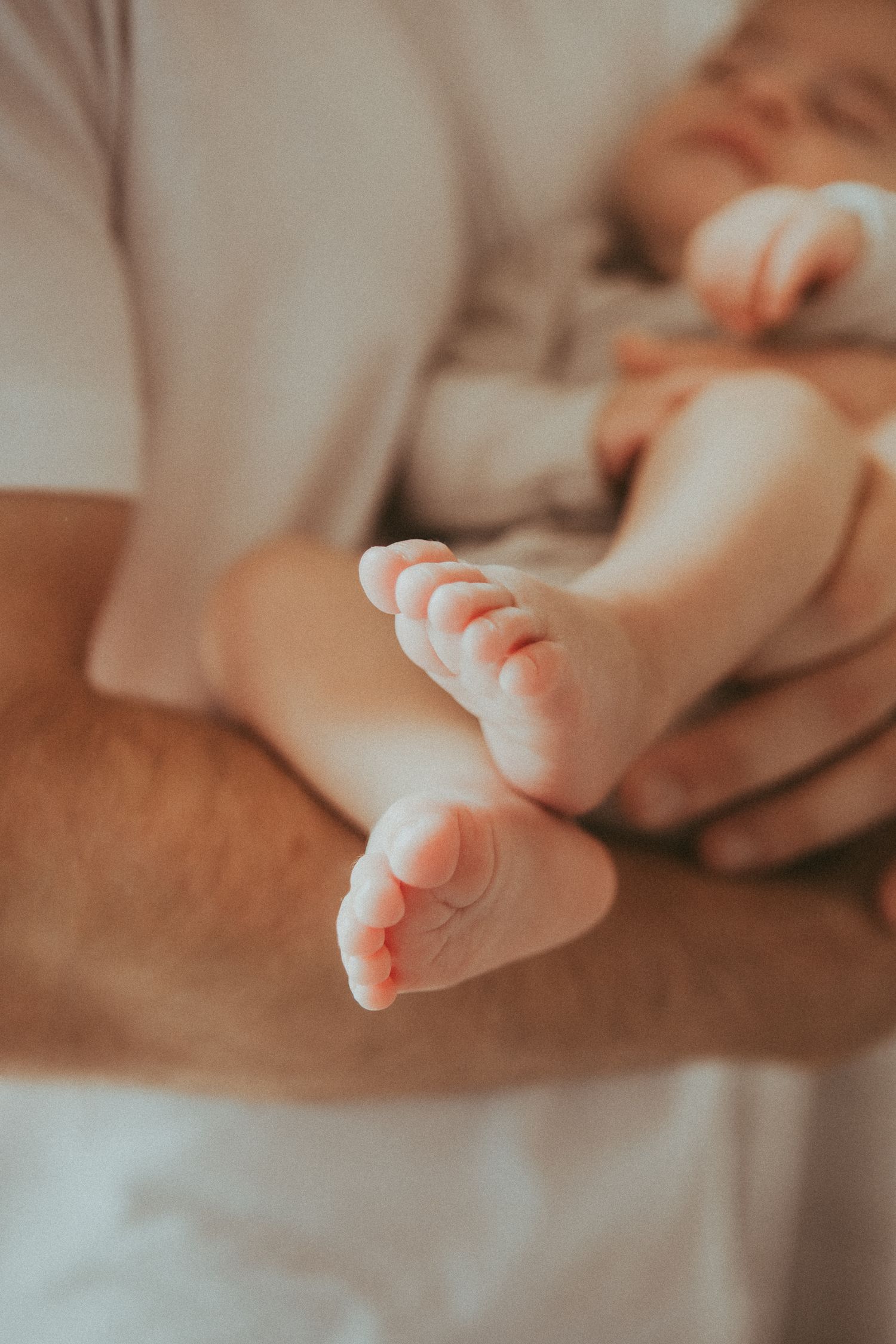 Close-up view of tiny newborn baby feet against a soft beige background.