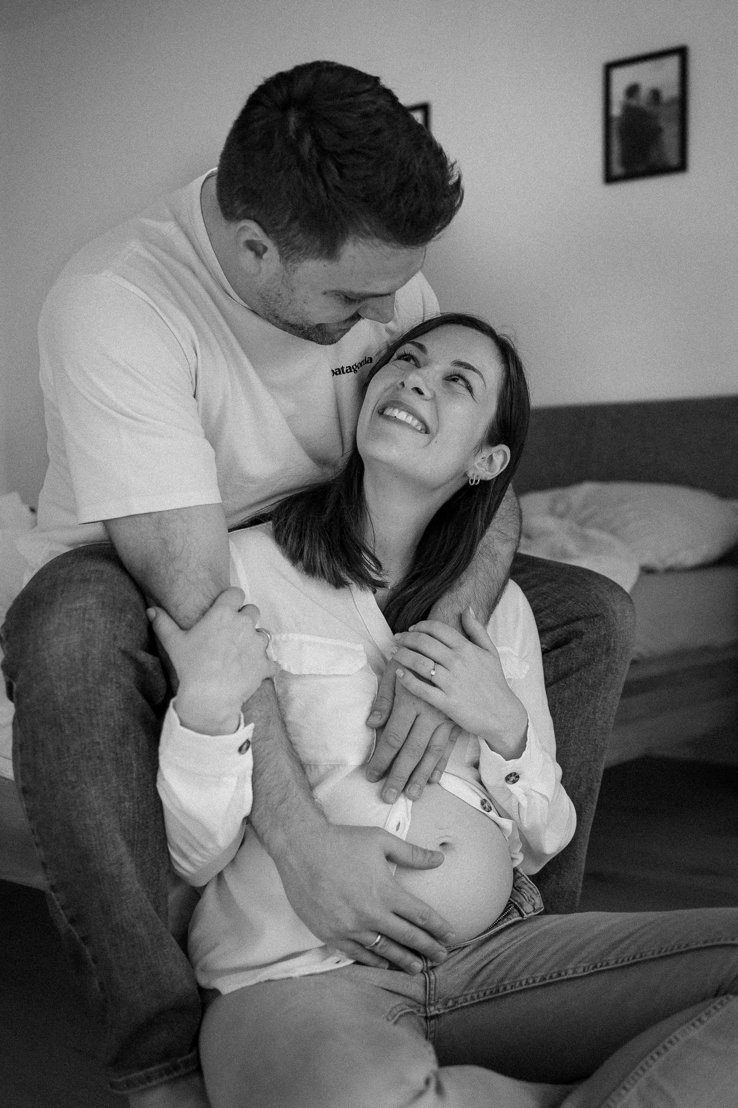 A loving couple shares intimate moments while relaxing together on a couch in black and white photography.